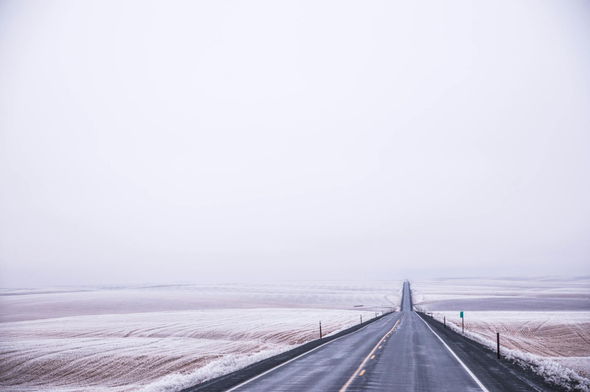 Long empty road stretching through snow-covered fields, capturing solitude and serenity. - long distance winter travel