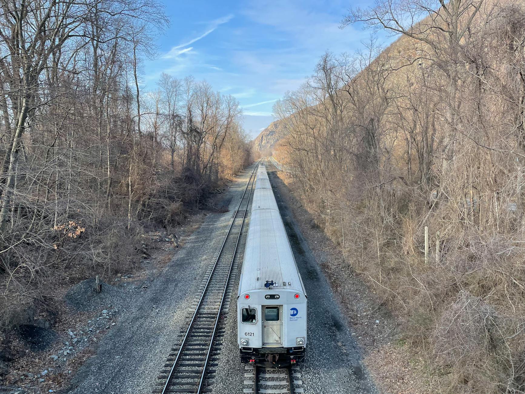 Train traveling through a forested area with bare trees and clear sky. Captured in winter. - long distance winter travel