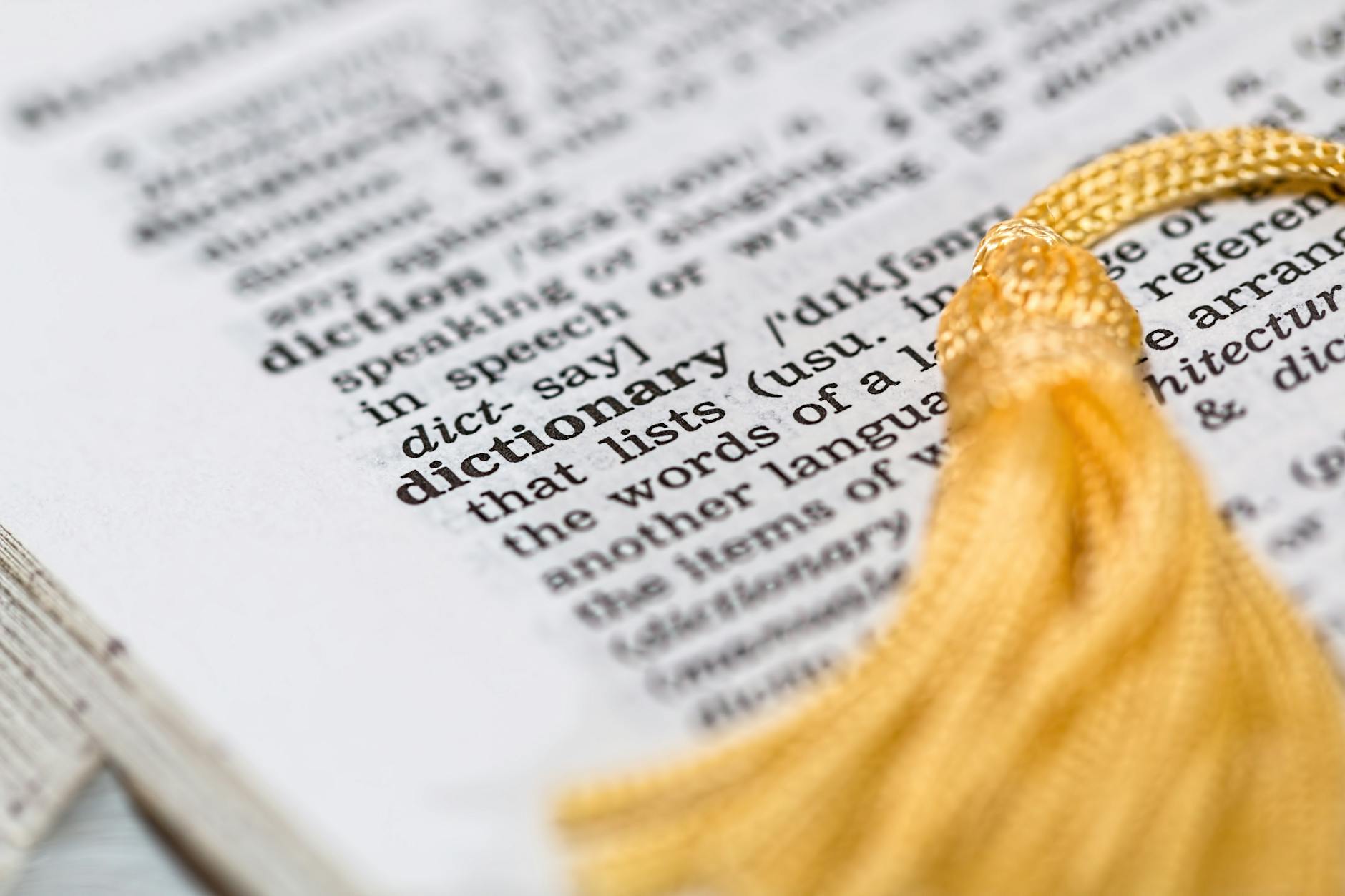 Close-up image of a dictionary page focused on the word 'dictionary' with a yellow tassel. - love bombing meaning