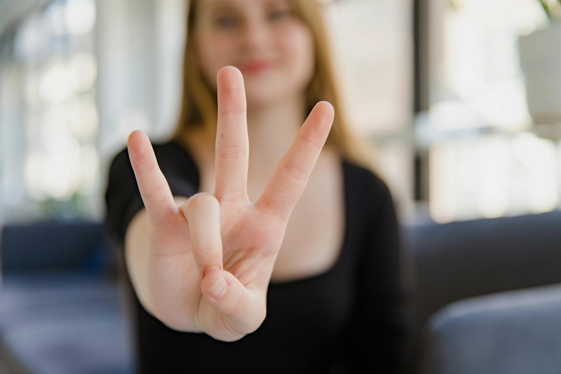 A close-up image of a woman making the ASL sign for 'I Love You' with focus on the hand gesture. - love language quiz