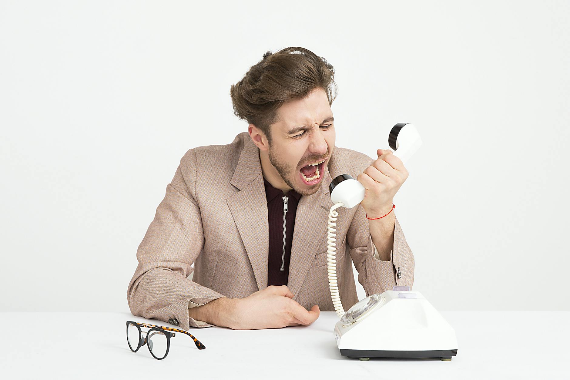 Businessman in a beige suit shouting into a vintage telephone, expressing frustration at work. - manage kids winter frustration