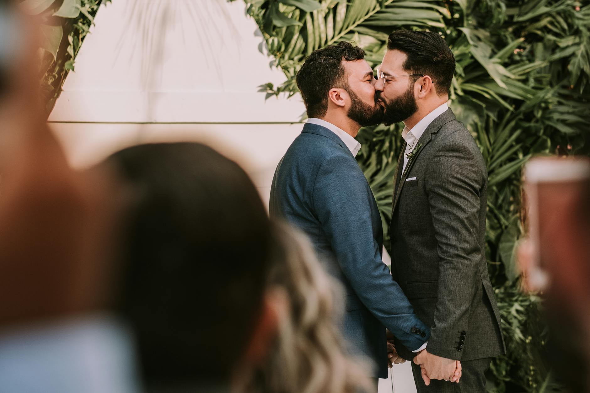 A same-sex couple shares a tender kiss at their wedding ceremony, celebrating love and commitment. - marriage advice for newlyweds