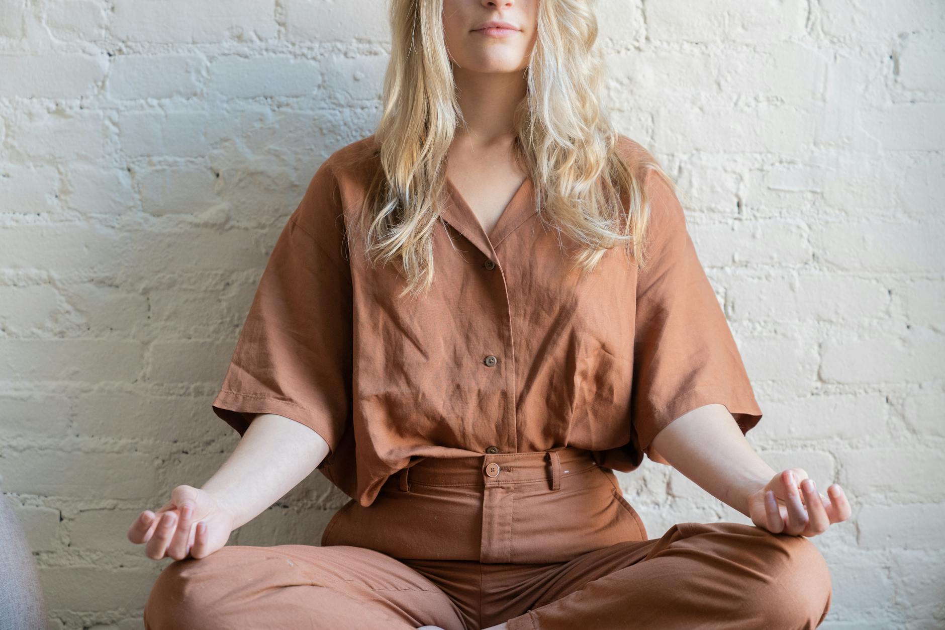 Woman meditating indoors, practicing mindfulness and relaxation techniques. - mindfulness techniques financial stress