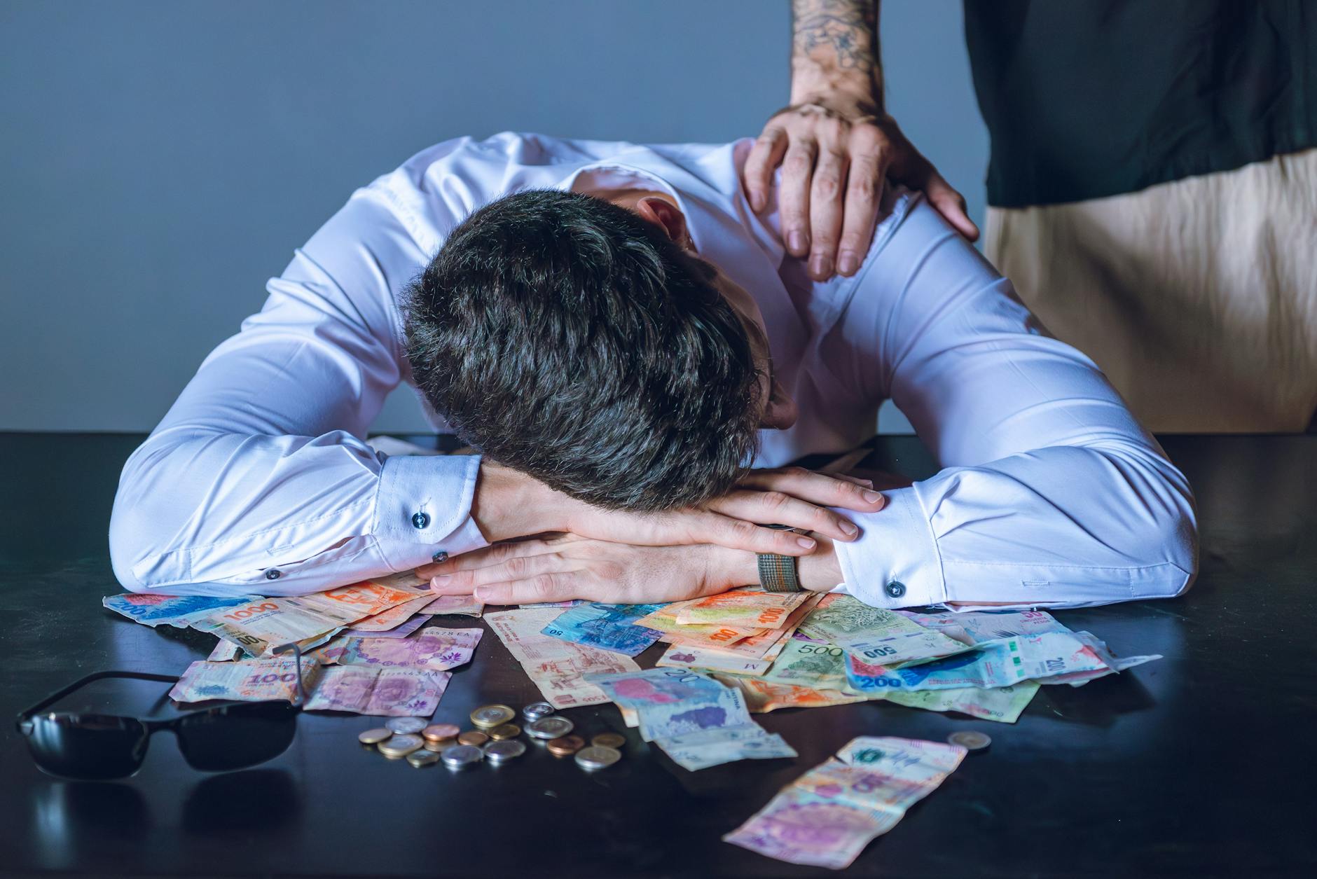 Stressed businessman rests on table with Argentine pesos in Buenos Aires. - mindfulness techniques financial stress