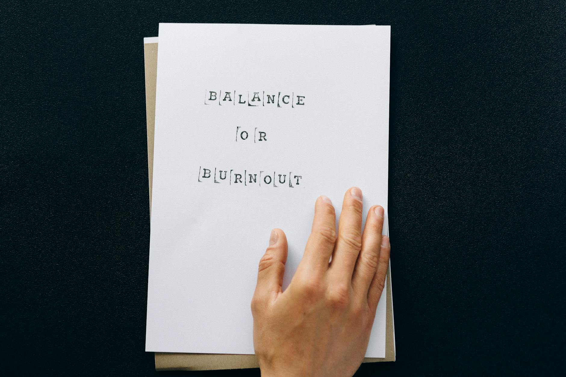 Hand holding paper with 'Balance or Burnout' text, promoting mental wellness. - mindfulness for winter anxiety