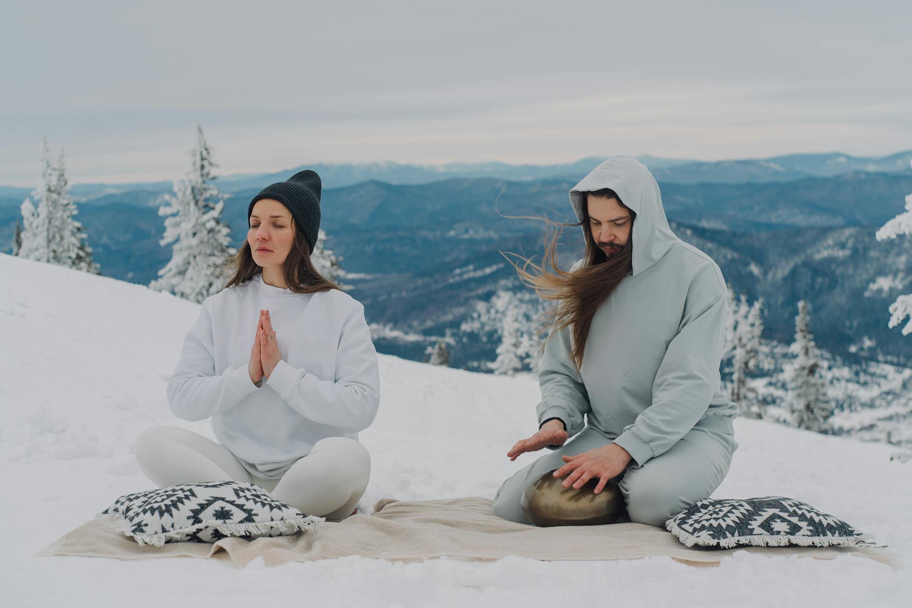Couple meditating in serene snowy landscape, embracing mindfulness in winter scenery. - mindfulness for winter blues