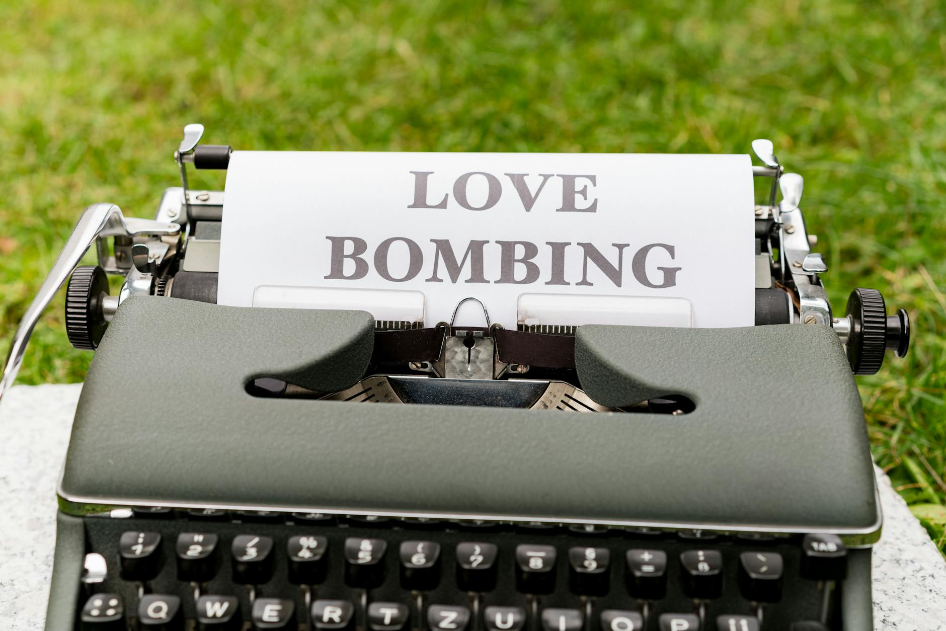 A vintage typewriter displaying the phrase 'Love Bombing' outdoors, symbolizing emotional manipulation. - narcissistic relationship signs