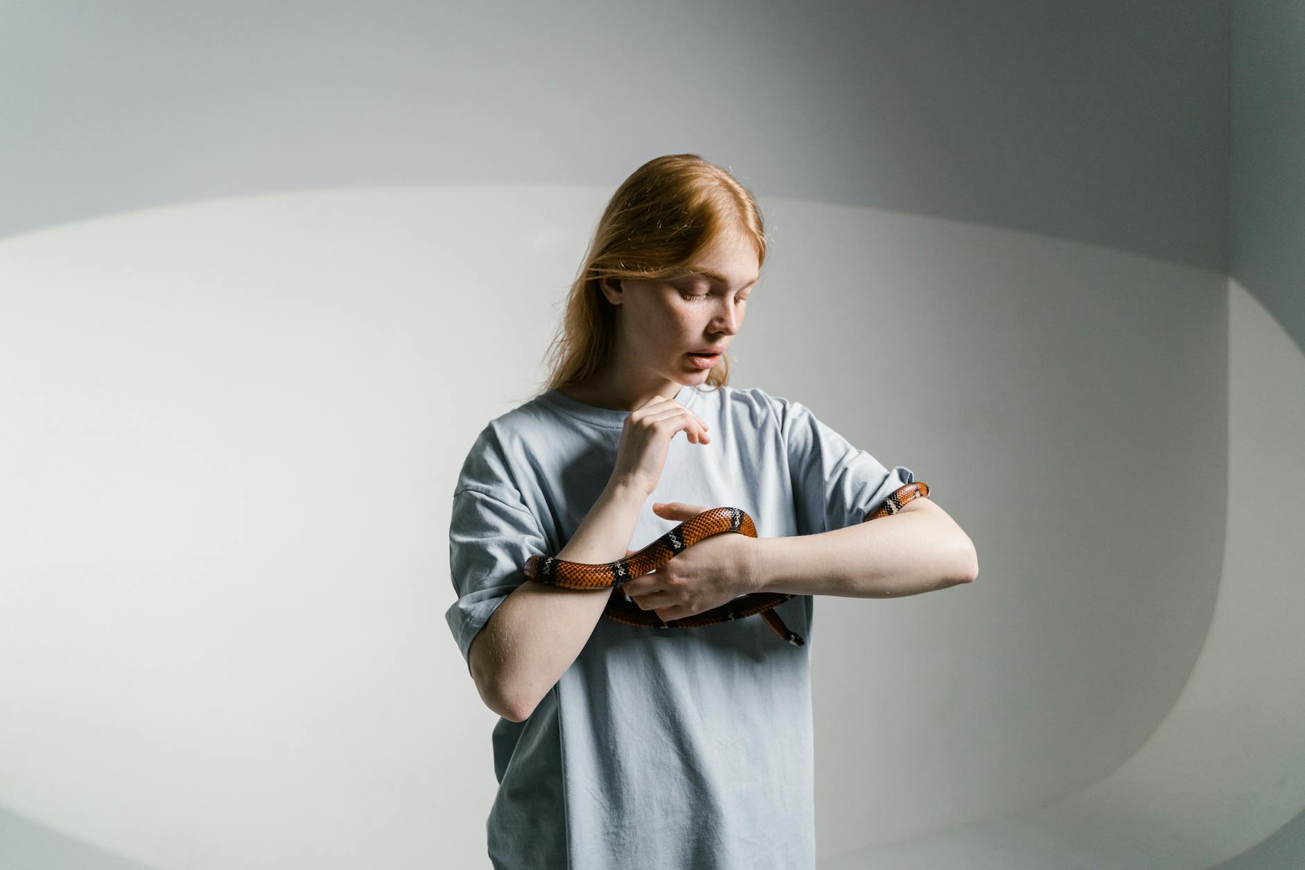 A woman calmly interacts with a snake in a well-lit indoor environment. - overcoming jealousy in relationships