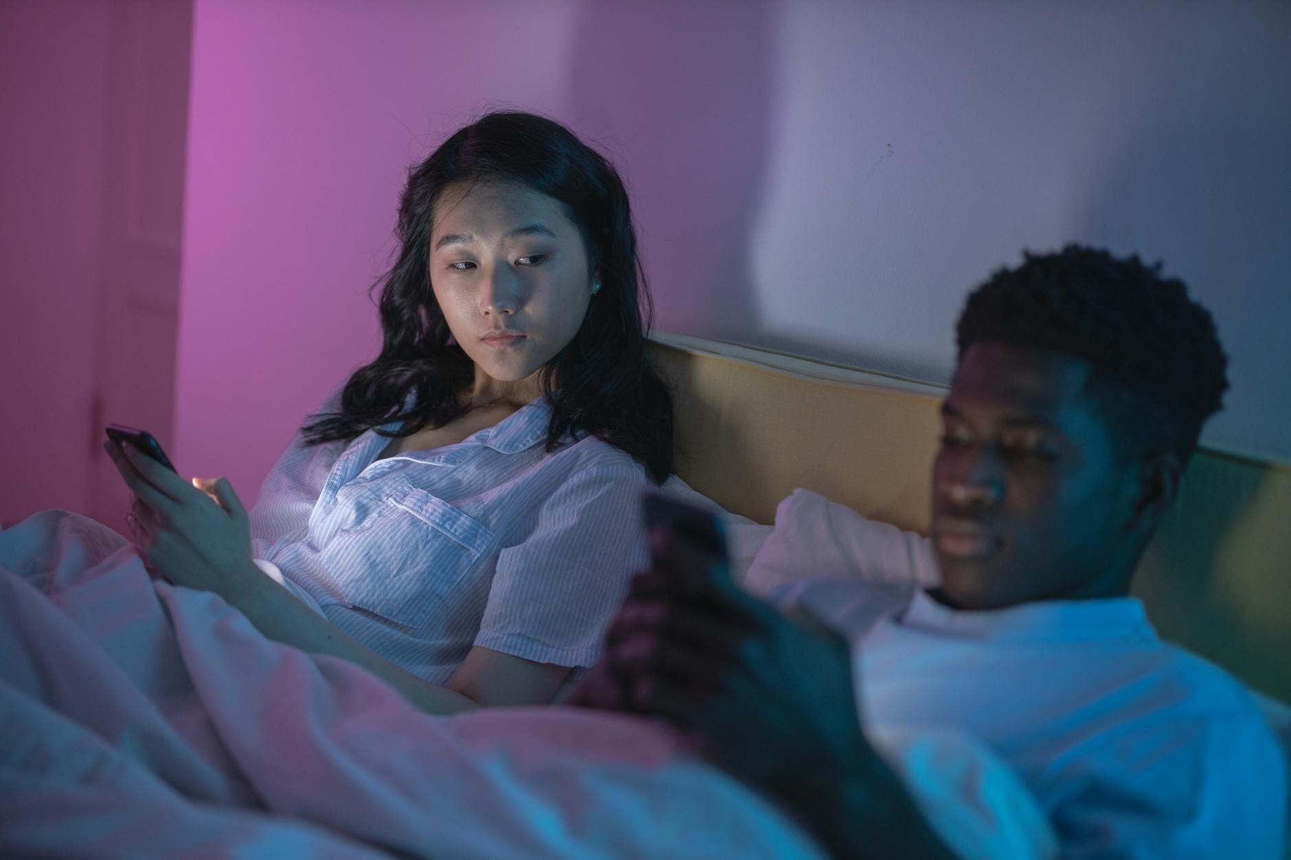 A couple in bed using smartphones, highlighting digital age connectivity or isolation. - overcoming jealousy in relationships