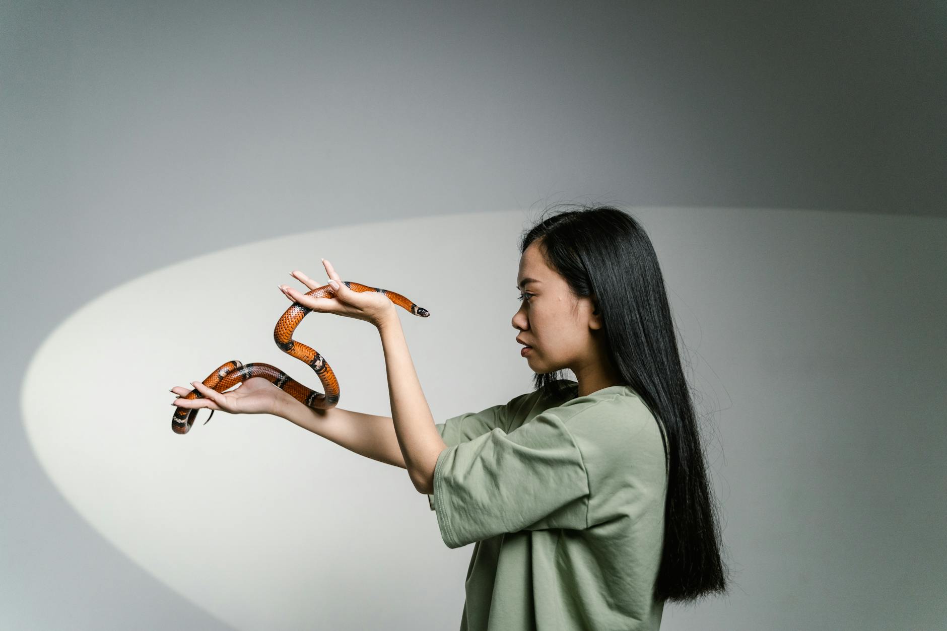 A woman confronting her fear by holding a snake, symbolizing overcoming anxiety. - overcoming winter perfectionism