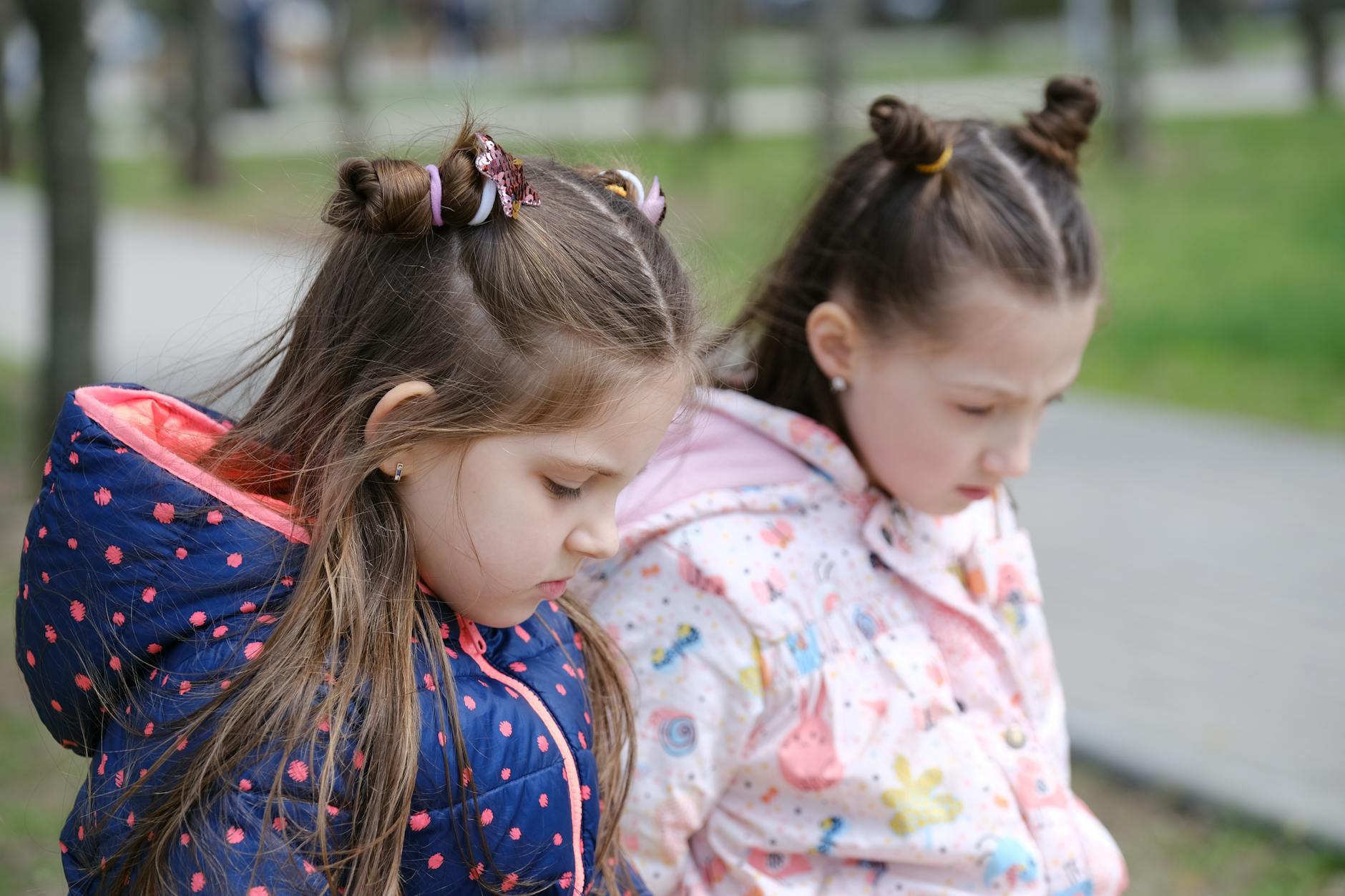 Two young girls in winter jackets, contemplative in a park setting. - post-holiday relationship regret