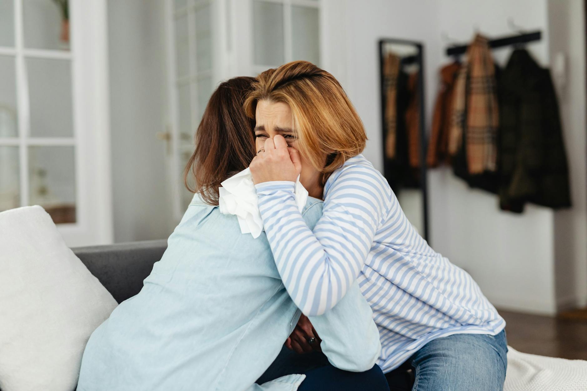 Two women hug indoors sharing emotional support. One woman is crying, comforted by the other. - rebuild intimacy after stress