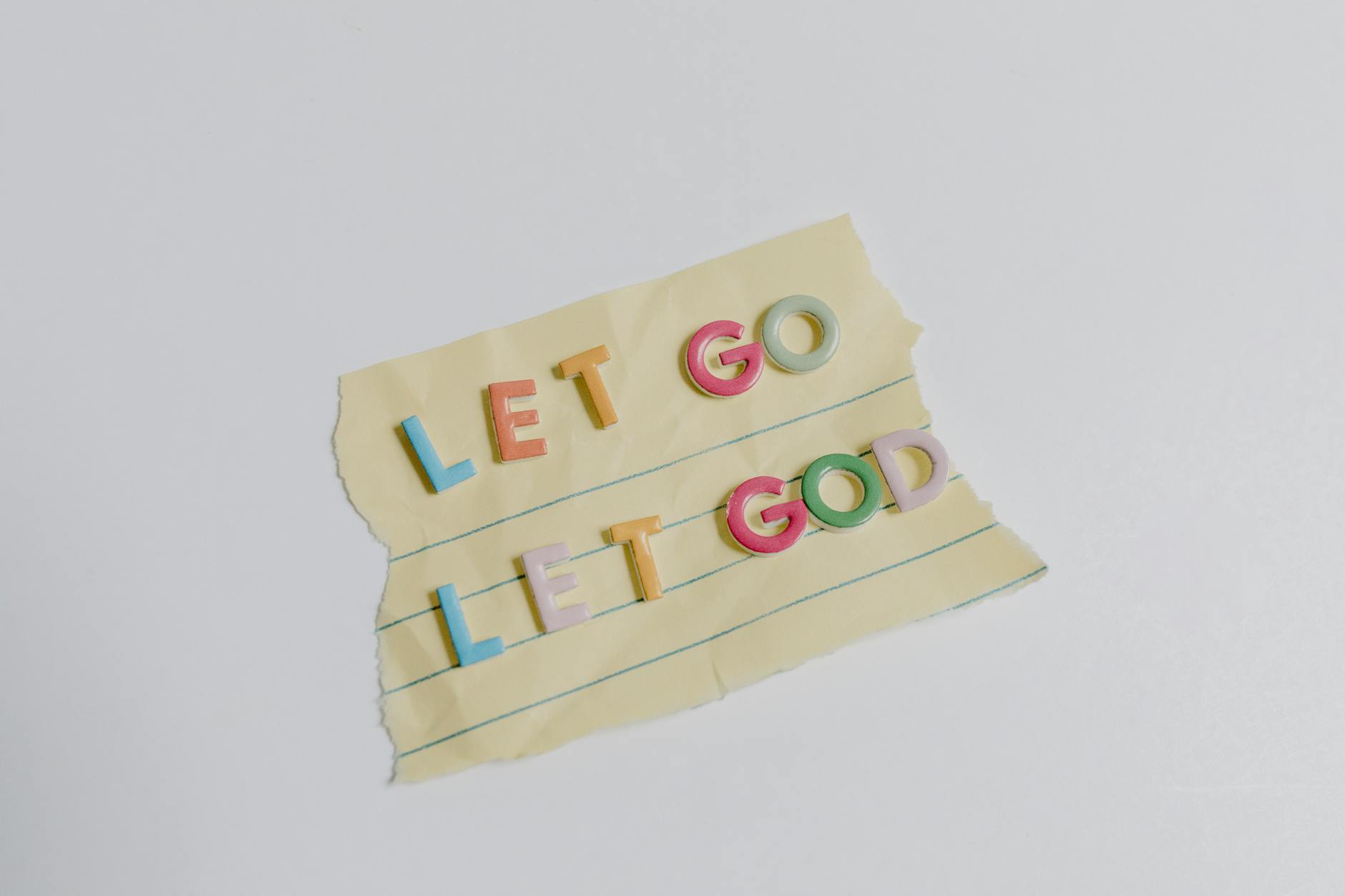 Colorful letters spell 'Let Go, Let God' on torn yellow lined paper. - rebuilding trust quotes