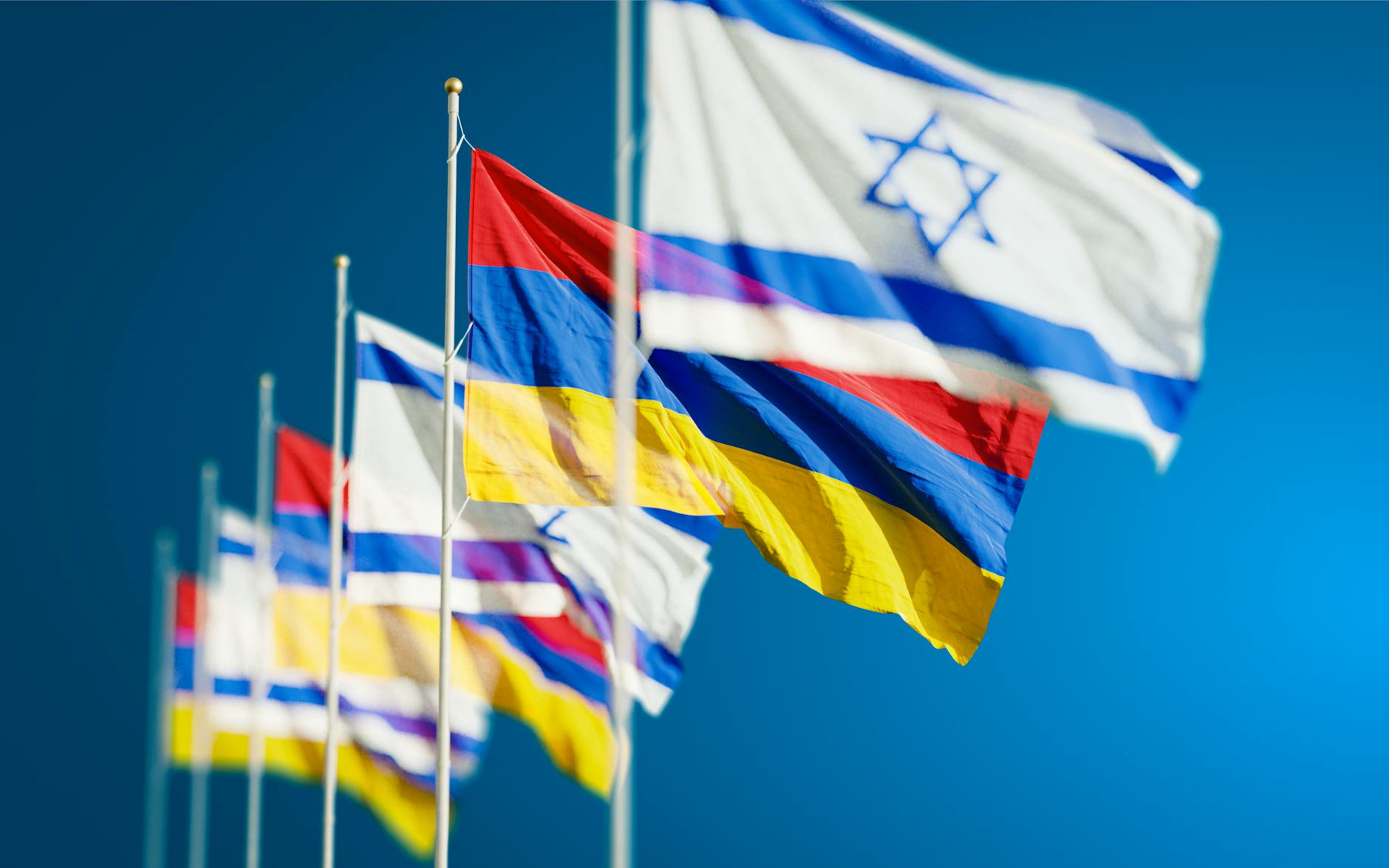 Vibrant national flags of Israel and Armenia waving against a clear blue sky. - relationship red flags