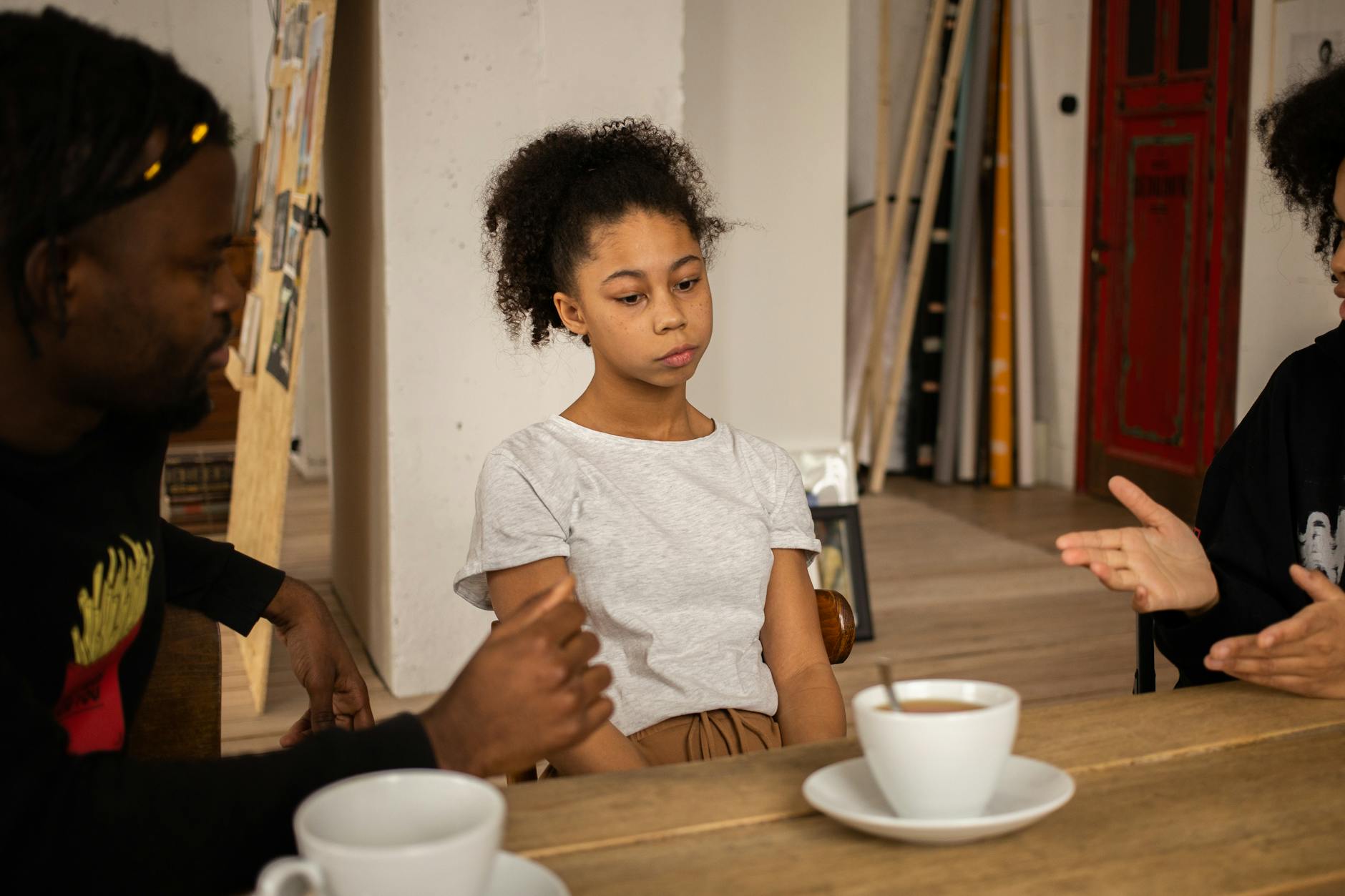 A family having a serious conversation at a table with coffee cups, highlighting a tense atmosphere indoors. - resolve vacation disagreements