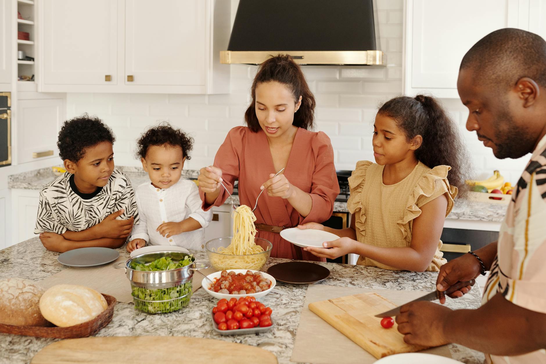 Family enjoying a cooking session together in a modern kitchen, preparing pasta and vegetables. - setting boundaries family gatherings