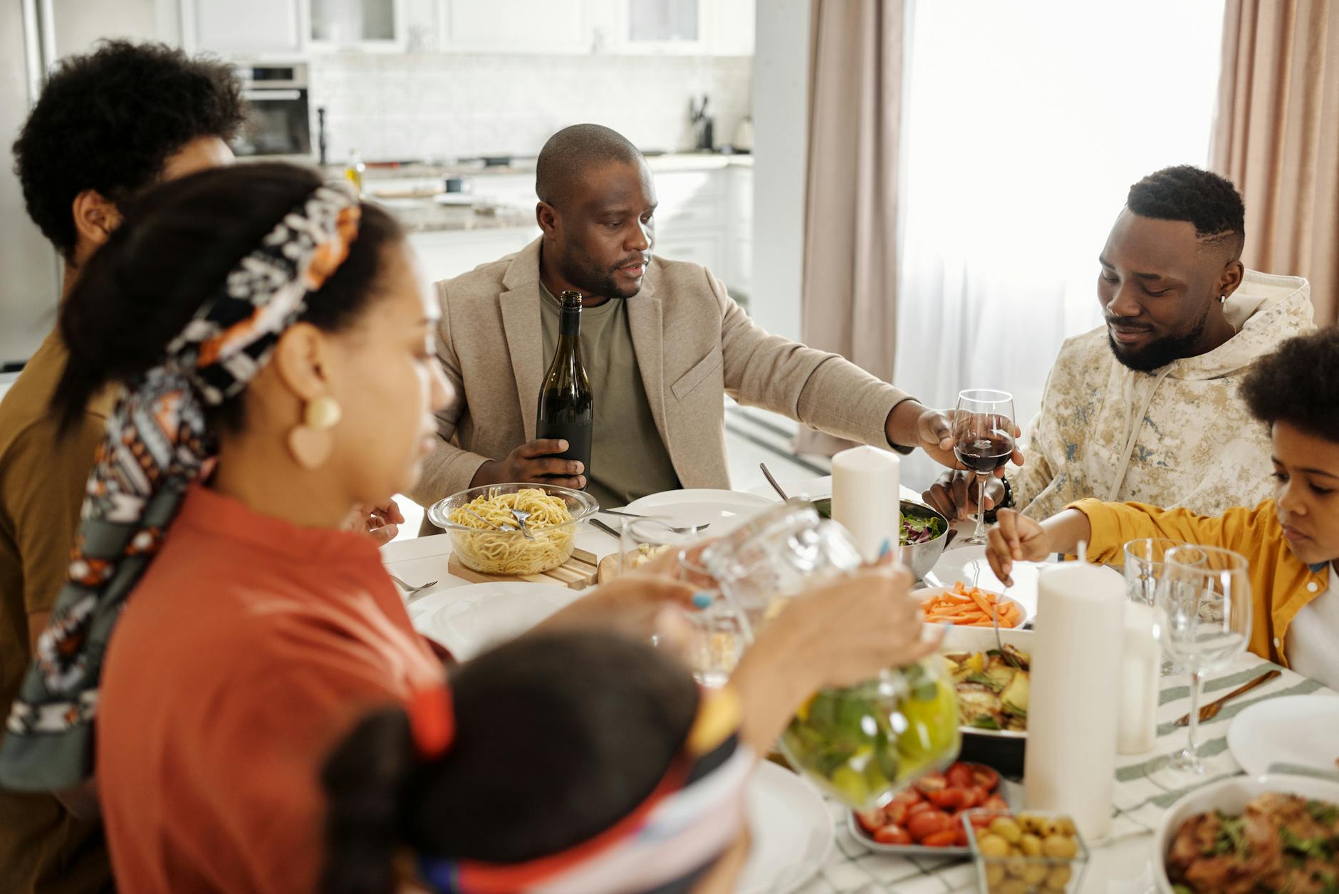 A cheerful family gathering around the dinner table enjoying food, wine, and togetherness. - setting boundaries family gatherings