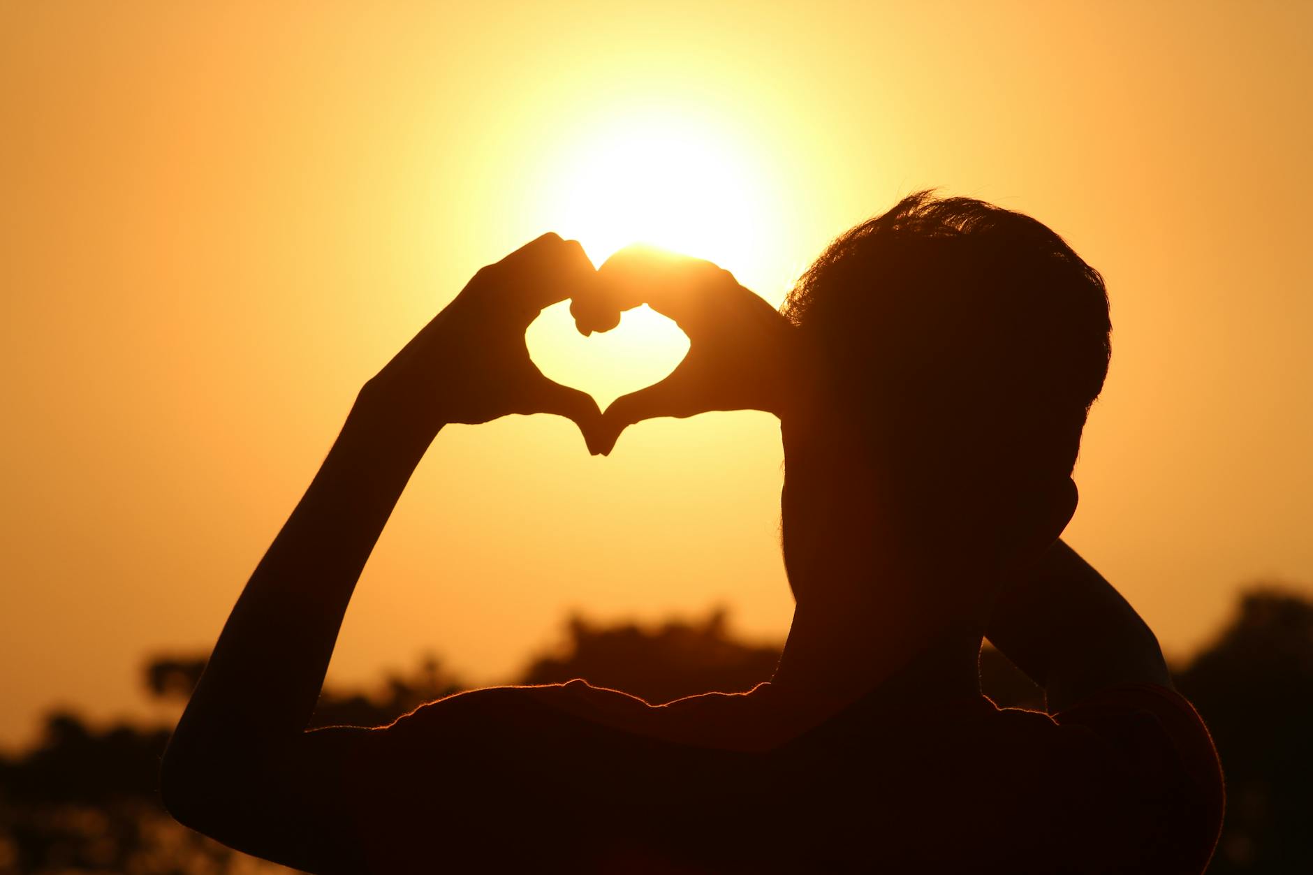 A silhouette of hands forming a heart shape against a vibrant sunset in Bangladesh. - setting relationship boundaries