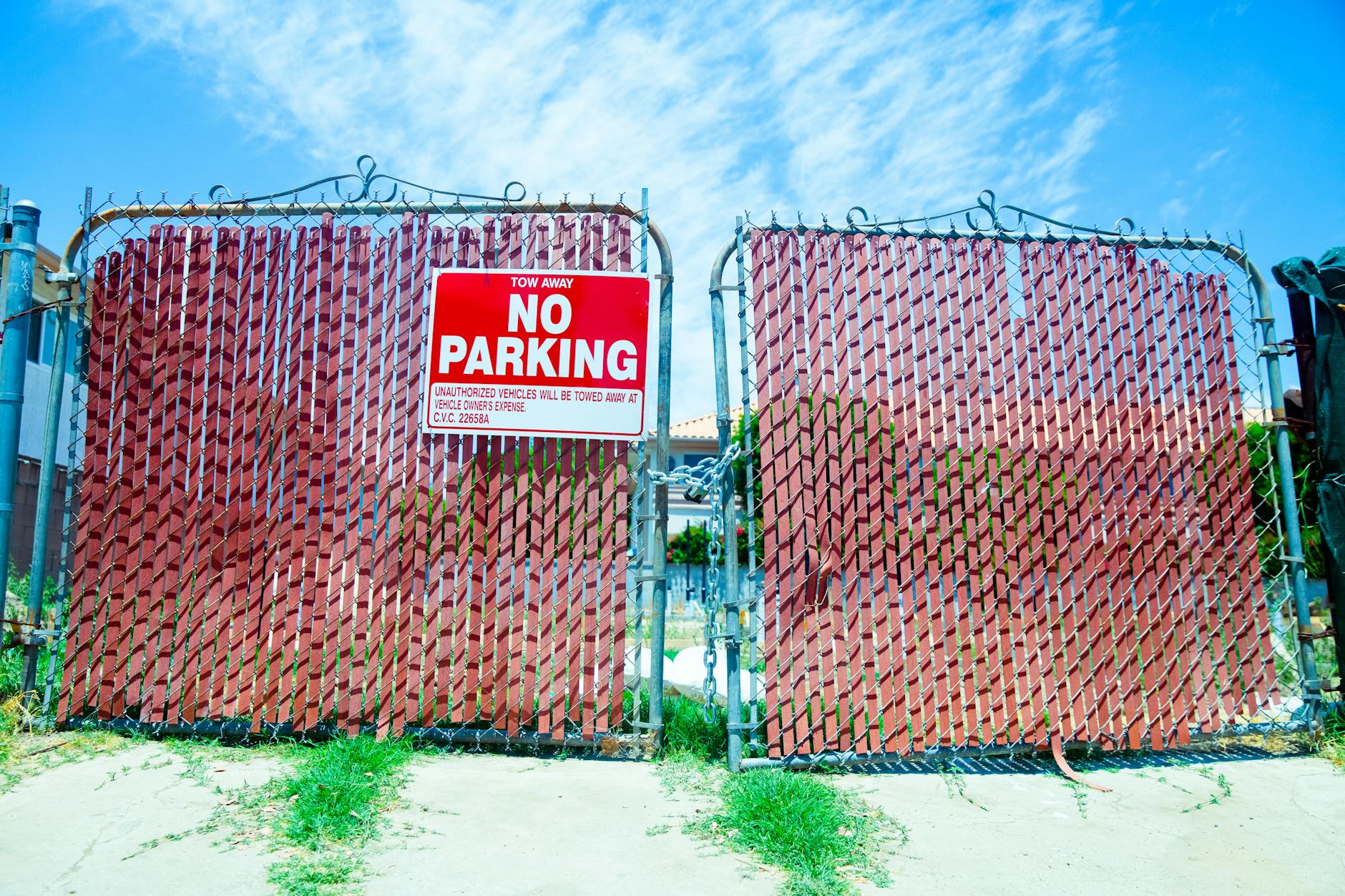 Red 'No Parking' sign on a metal gate with a vibrant blue sky background. - setting relationship boundaries