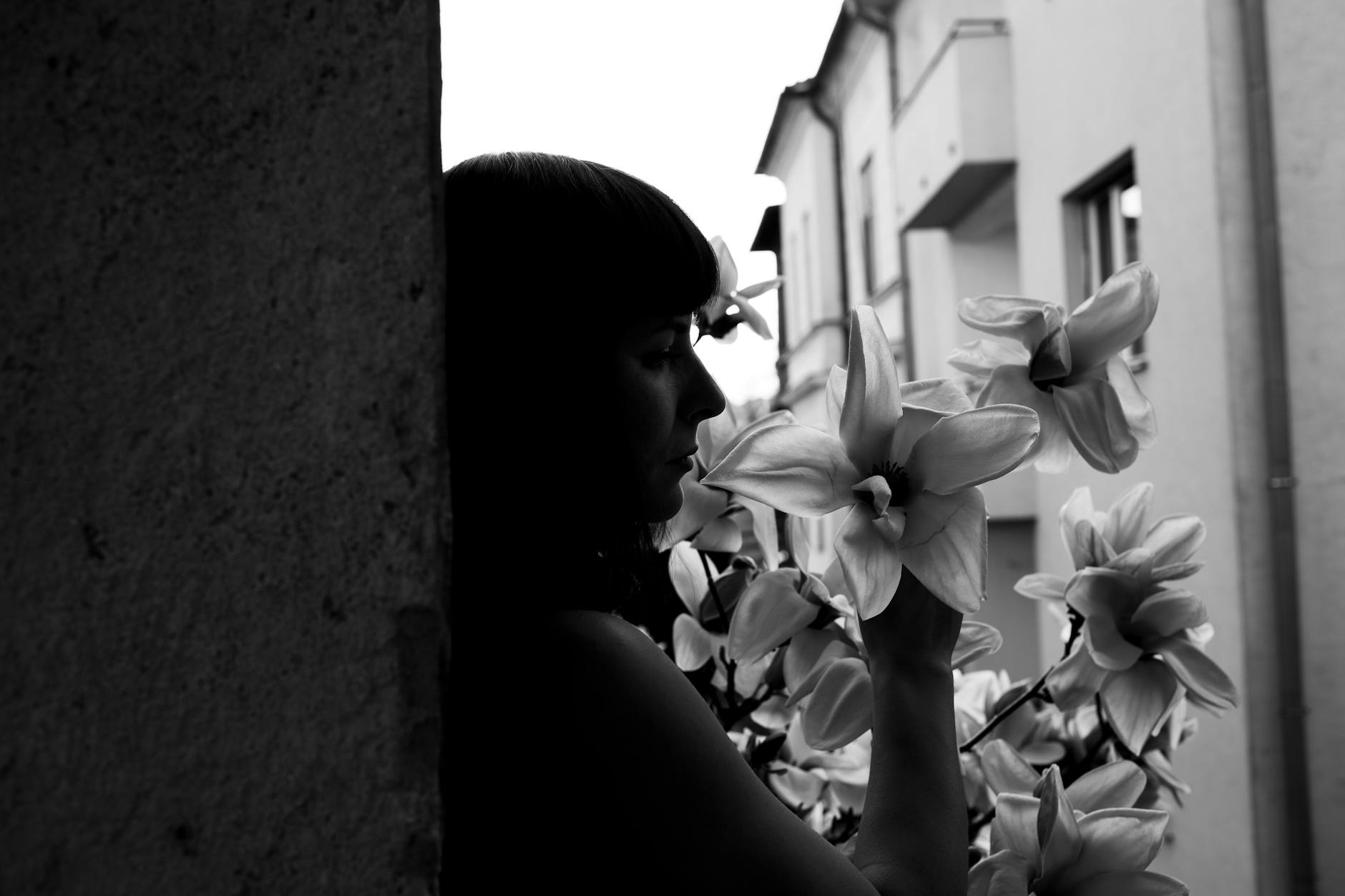 Black and white portrait of a woman contemplating in an urban setting with lilies. - therapy for winter apathy