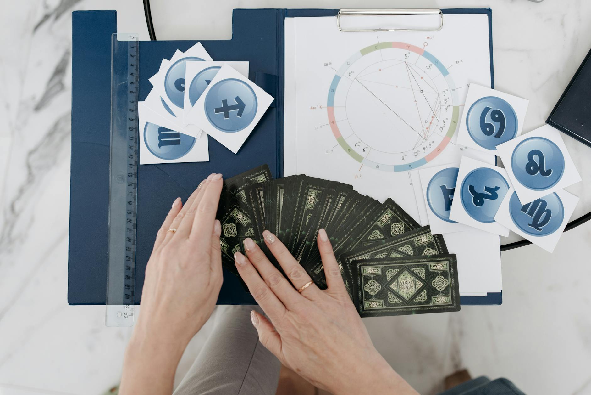 Hands arranging tarot cards with astrology symbols and natal chart on a table. - toxic relationship zodiac signs