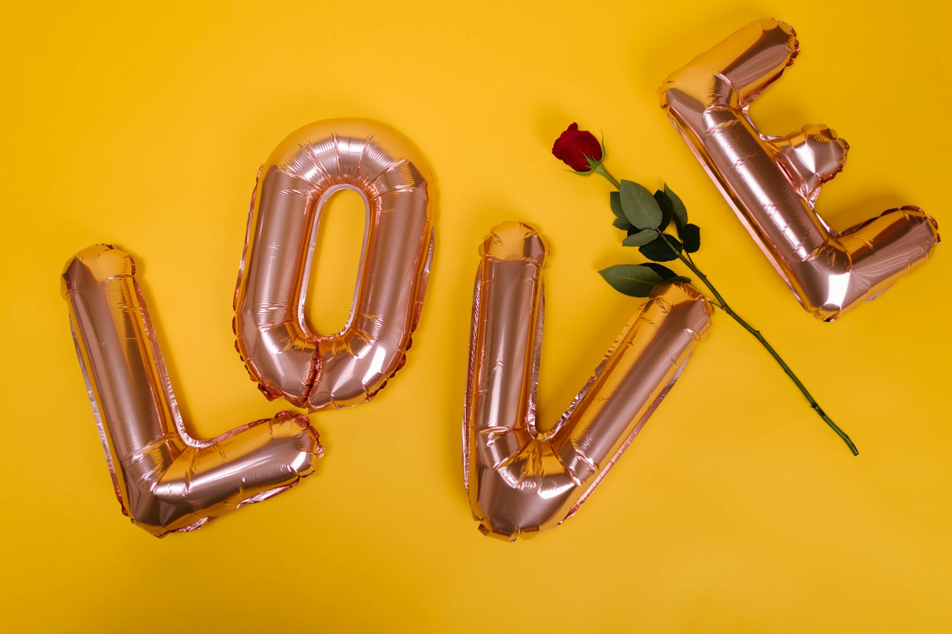Valentine's Day theme with love balloons and red rose on a yellow background. - valentine's day long distance ideas