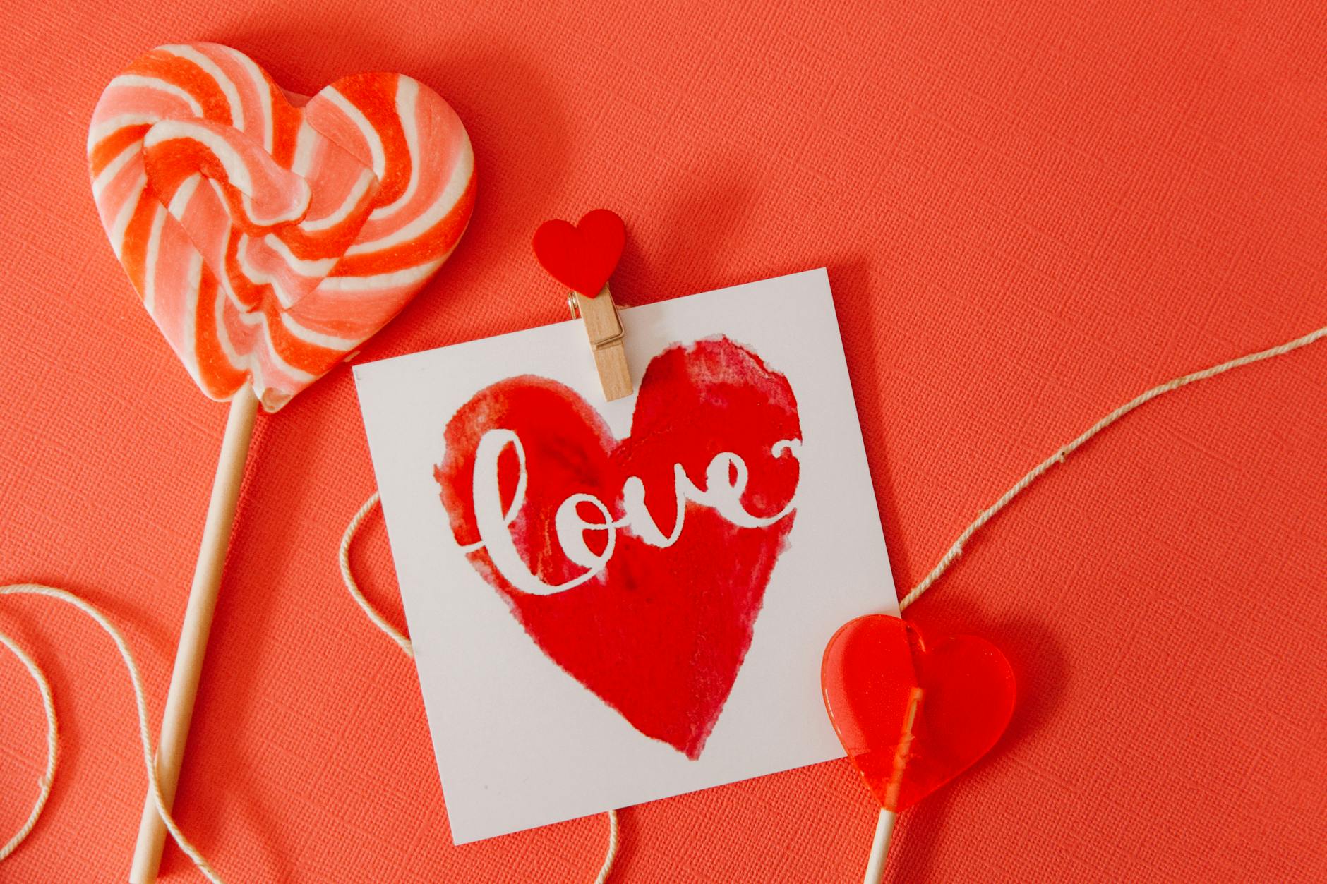 Heart-shaped lollipops and a 'love' card on a red background, perfect for Valentine's Day. - valentine's day long distance ideas