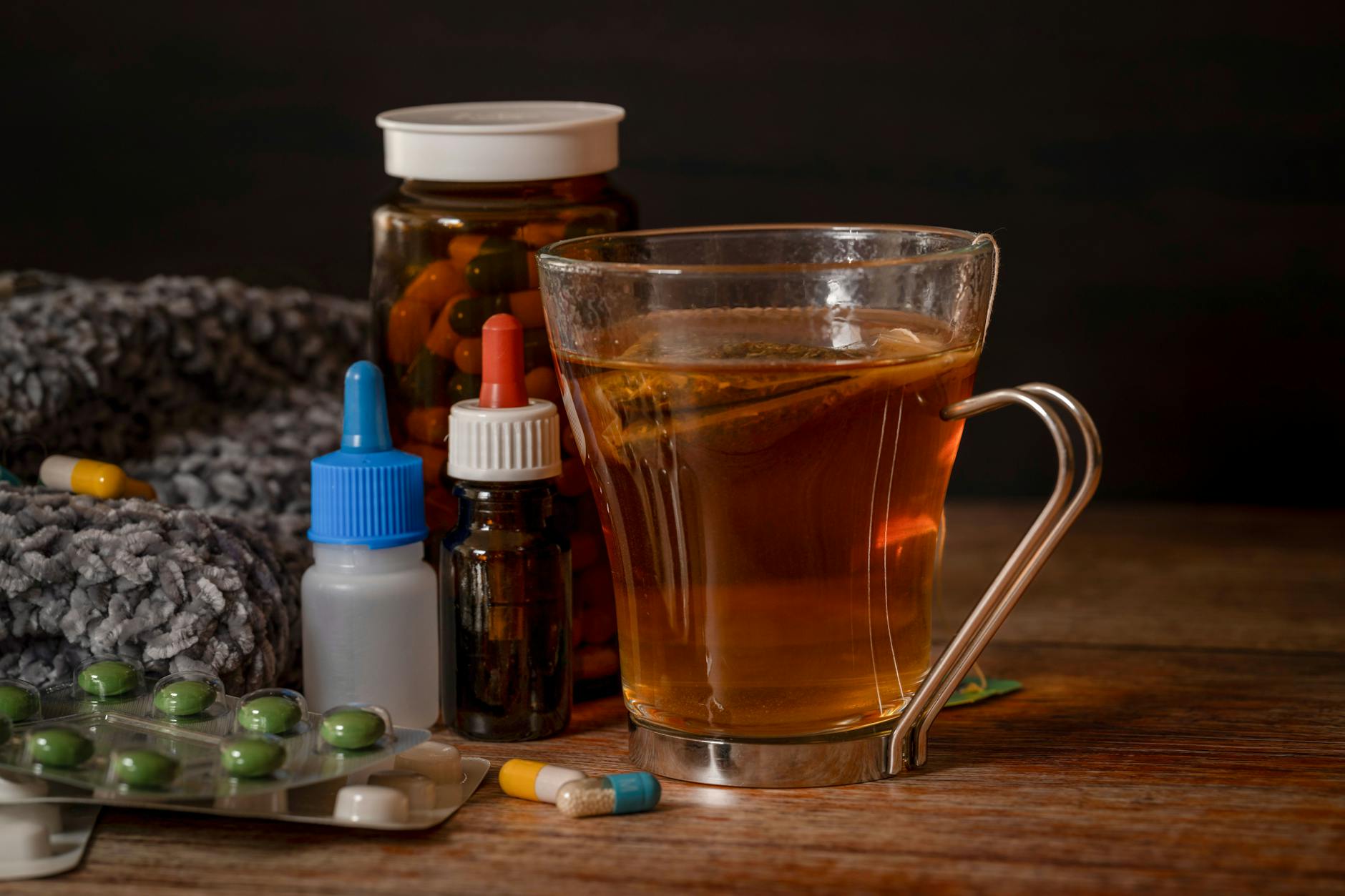 A cup of herbal tea with medications suggests natural cold remedies for healing. - winter blues natural remedies