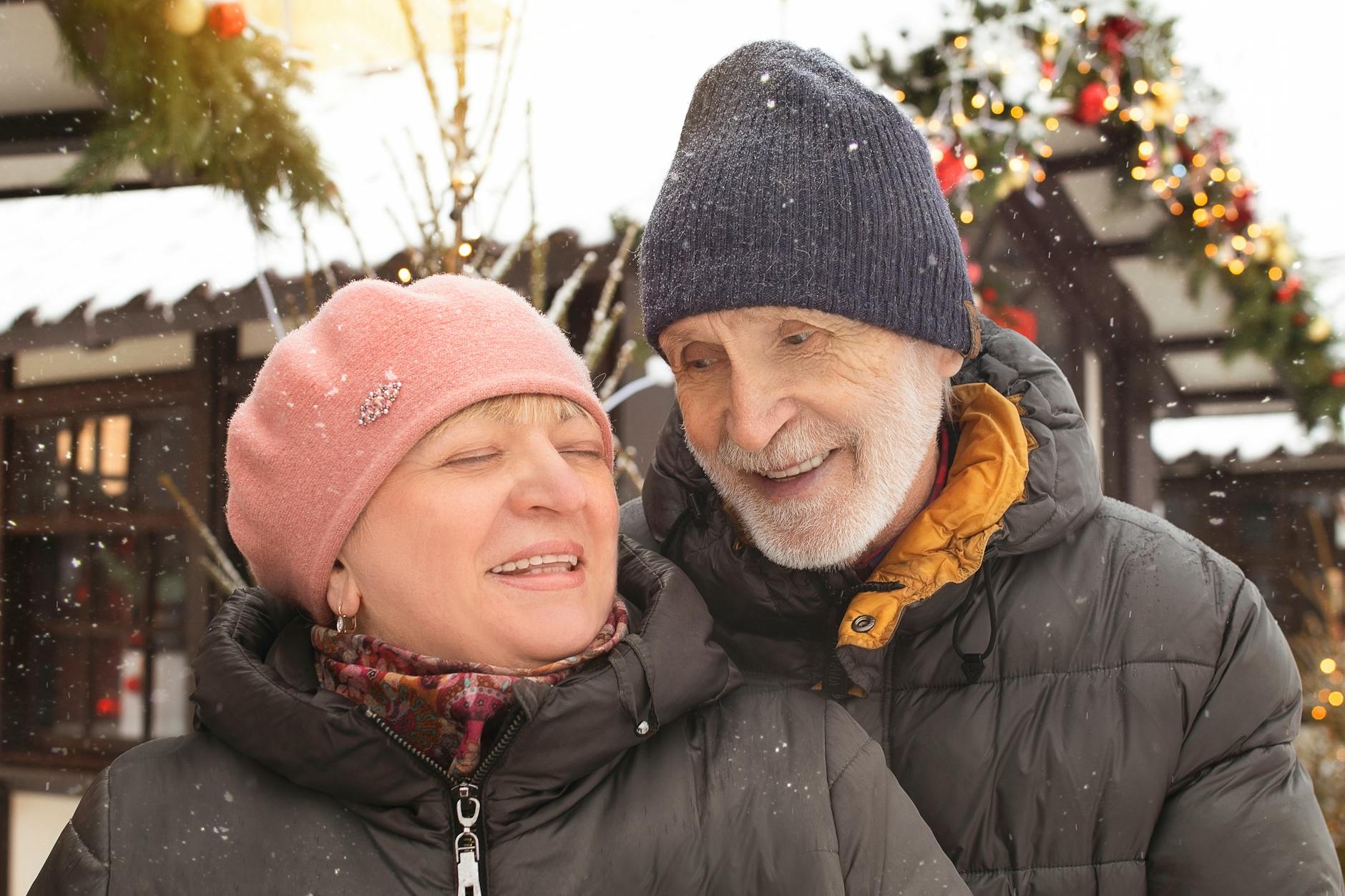 Joyful elderly couple enjoying a snowy winter day outdoors, dressed warmly in winter clothing. - winter happiness couples