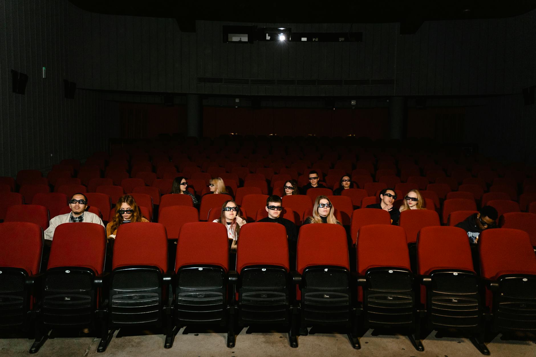 People watching a movie wearing 3D glasses in a near-empty cinema hall. - winter indoor activities no screens