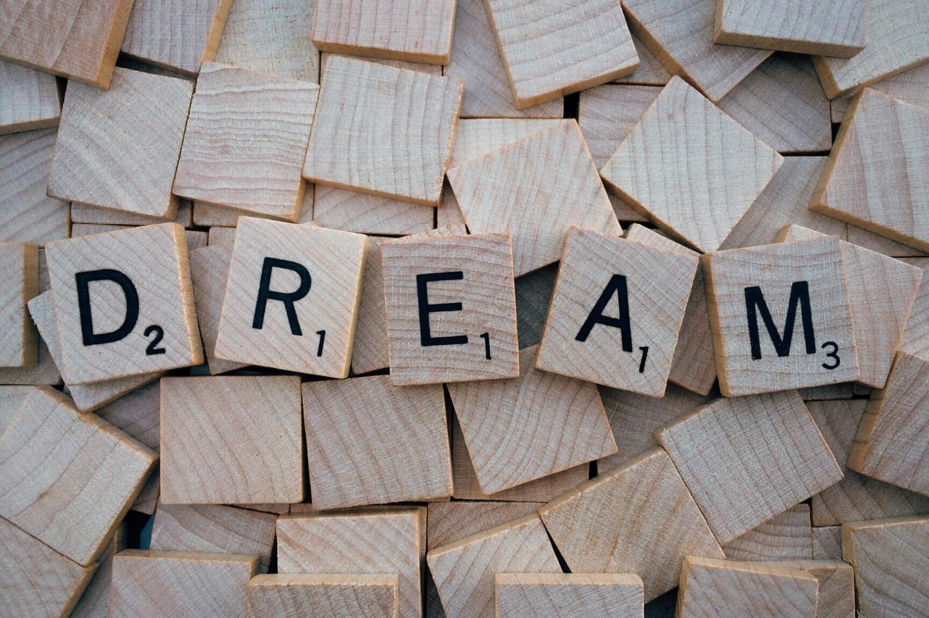 Close-up of wooden Scrabble tiles spelling the word 'DREAM', symbolizing creativity and imagination. - winter love languages ideas
