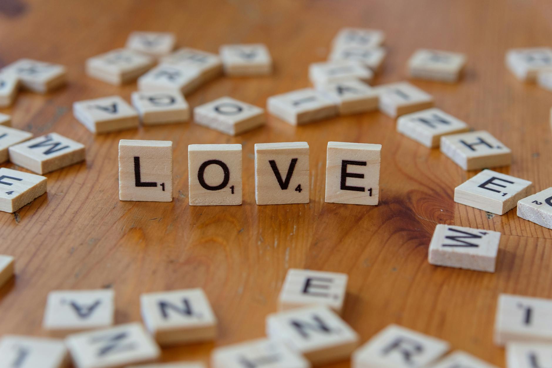 Scrabble tiles arranged to spell 'LOVE' on a wooden table, symbolizing affection and warmth. - winter love languages ideas