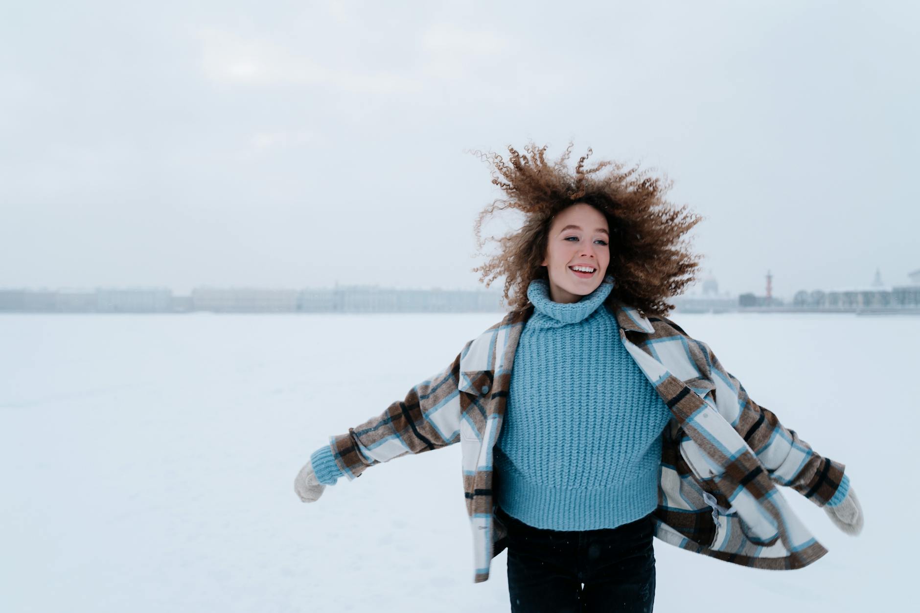 A young woman in a blue sweater enjoying a snowy winter day outdoors. - winter mood boost activities