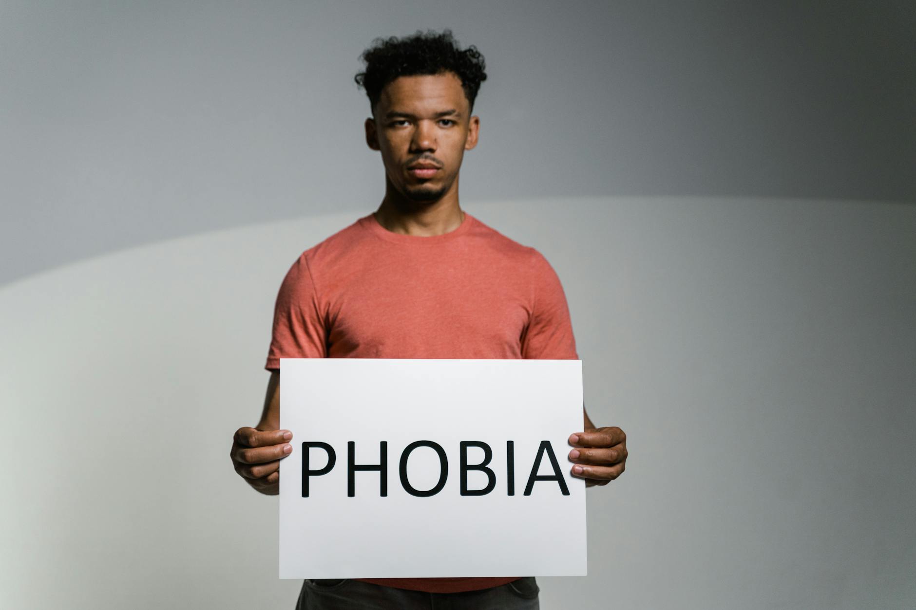 A man holding a sign that reads 'PHOBIA' symbolizes awareness and feelings of fear and anxiety. - winter social anxiety
