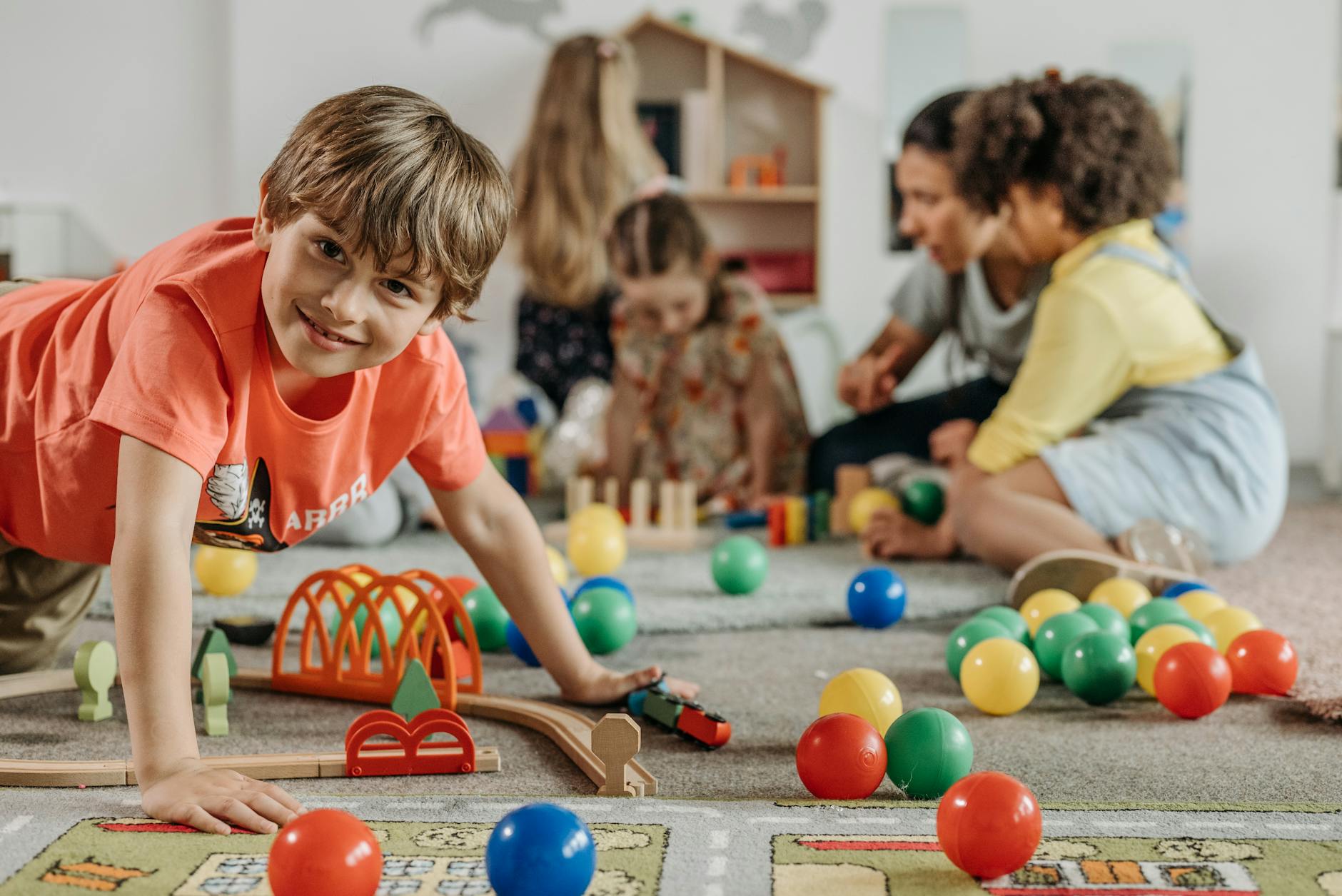 Happy children and a caregiver playing with colorful toys in a lively indoor playroom setting. - winter social skills for kids