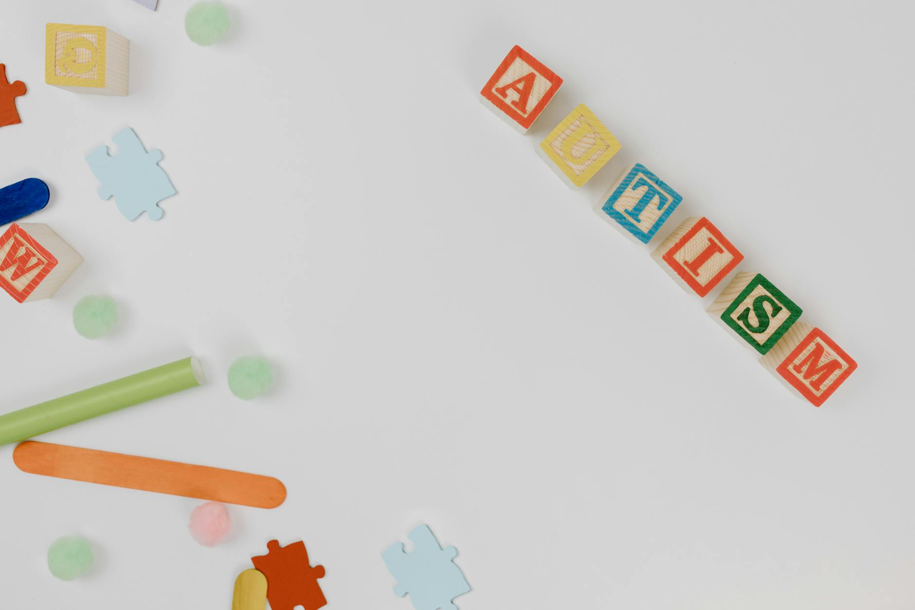 Top view of colorful wooden blocks spelling 'autism' surrounded by puzzle pieces symbolizing autism awareness. - acceptance and commitment therapy spring