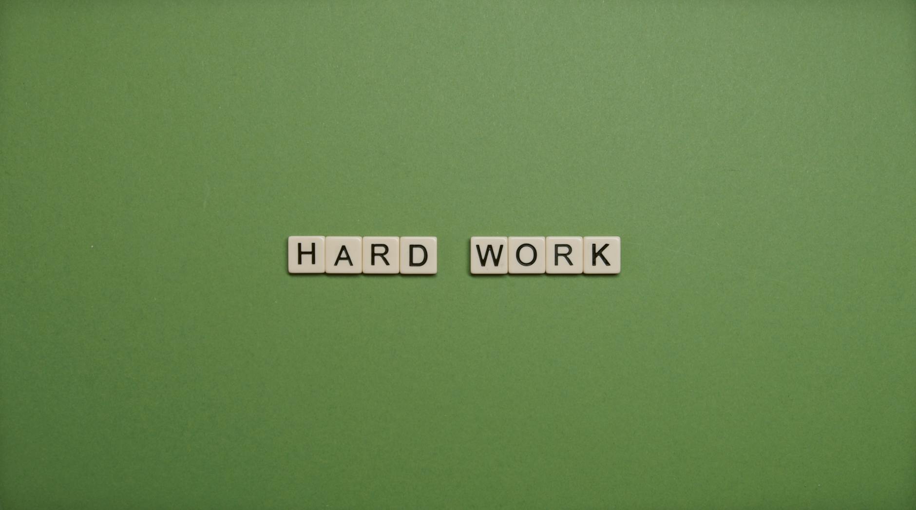 Tiles spelling 'hard work' on a green background symbolizing diligence and effort. - achievable therapy goals