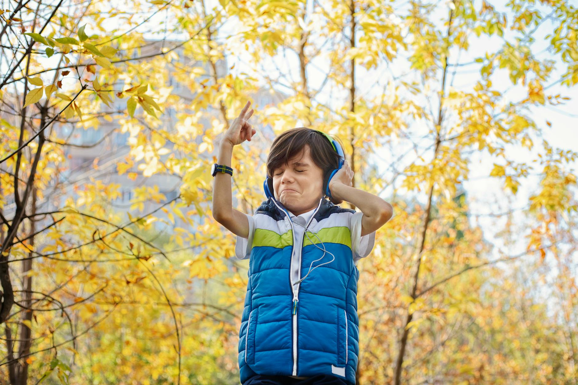 A young boy with headphones enjoying music in a vibrant autumn park setting. - active listening definition