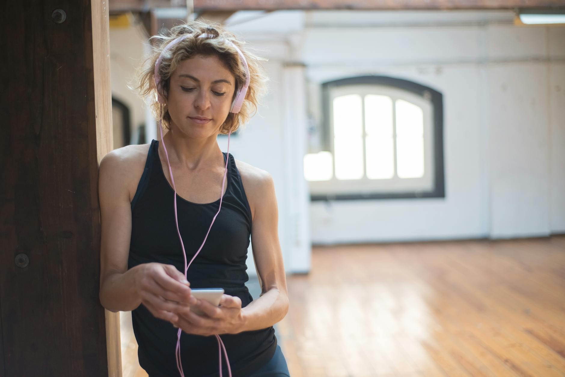 Blonde woman in a dance studio listening to music on her phone, conveying a serene and focused ambiance. - active listening definition