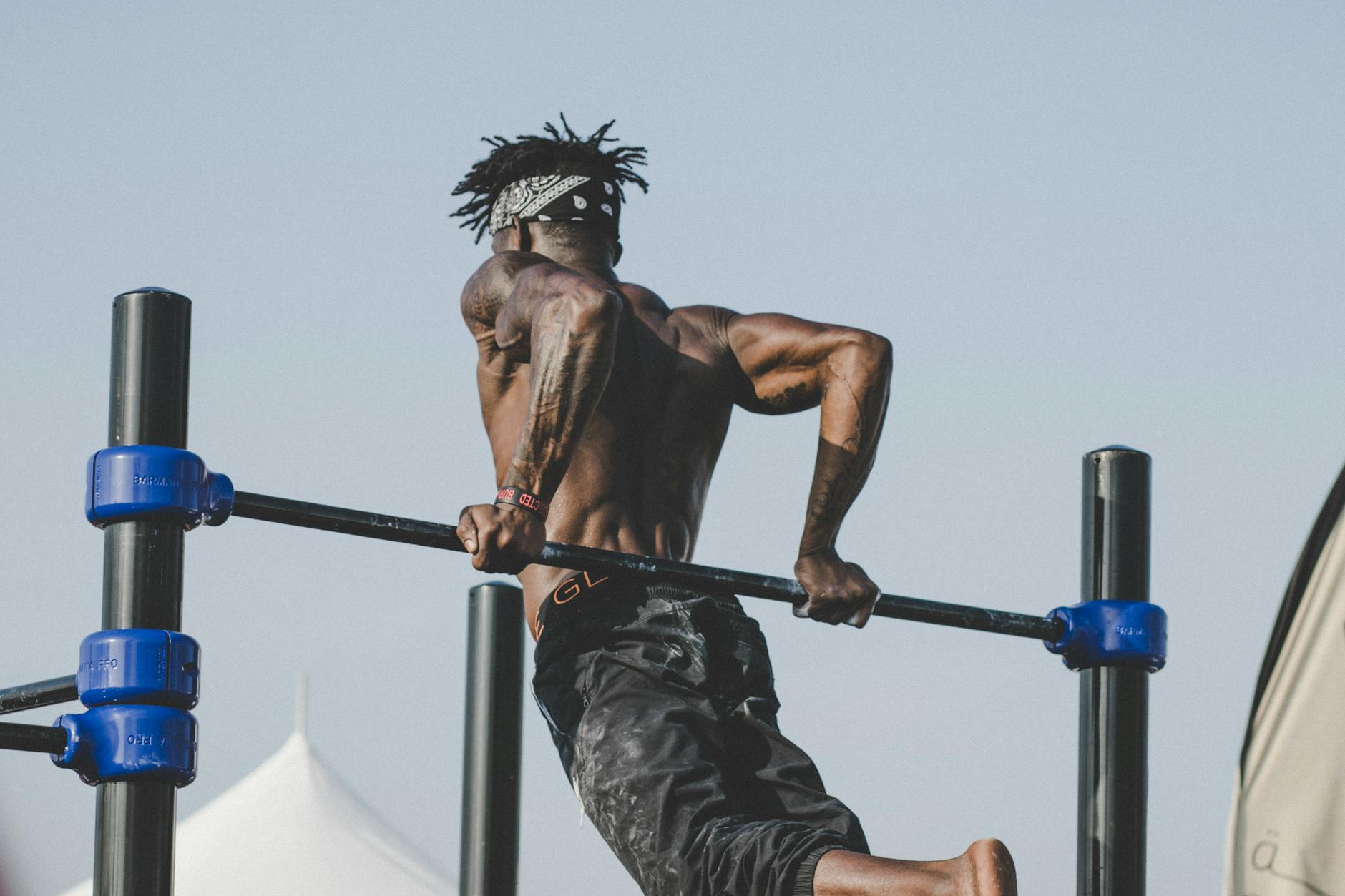 Muscular man exercising on a pull-up bar outdoors, showcasing strength and fitness. - active listening definition