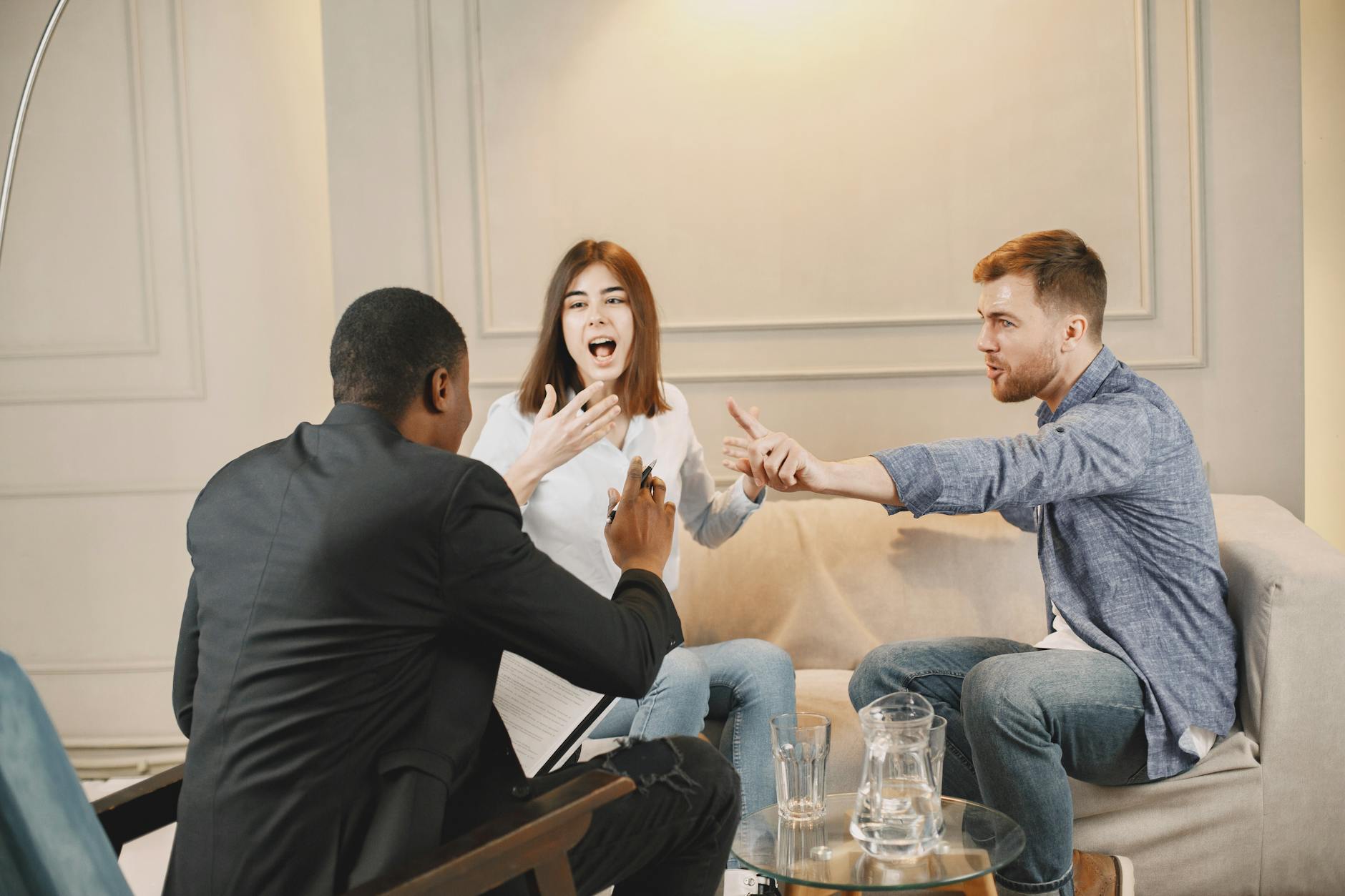 Three adults engaged in a lively discussion indoors, showcasing active communication and expression. - active listening difficult conversations