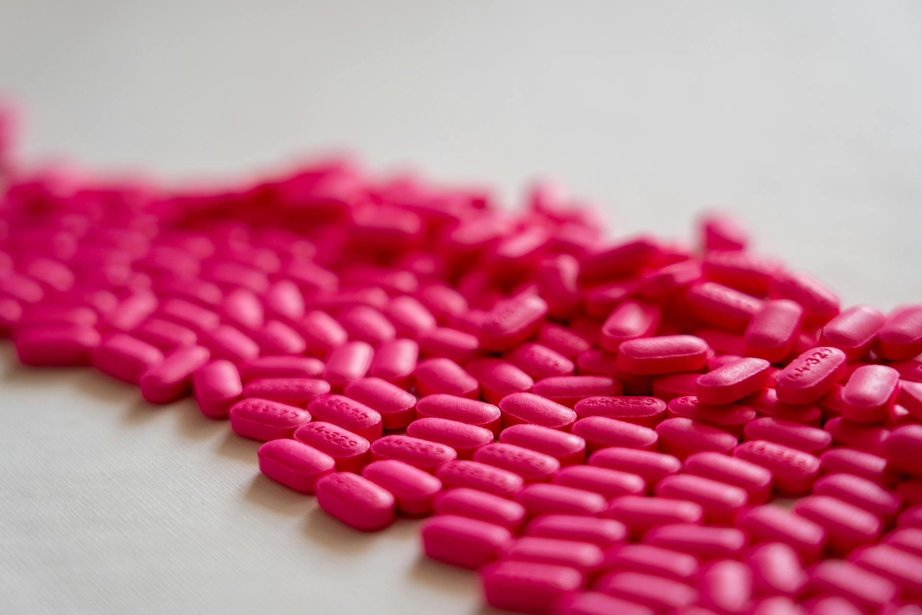 A close-up shot of scattered neon pink pills on a white surface. - allergy mental health
