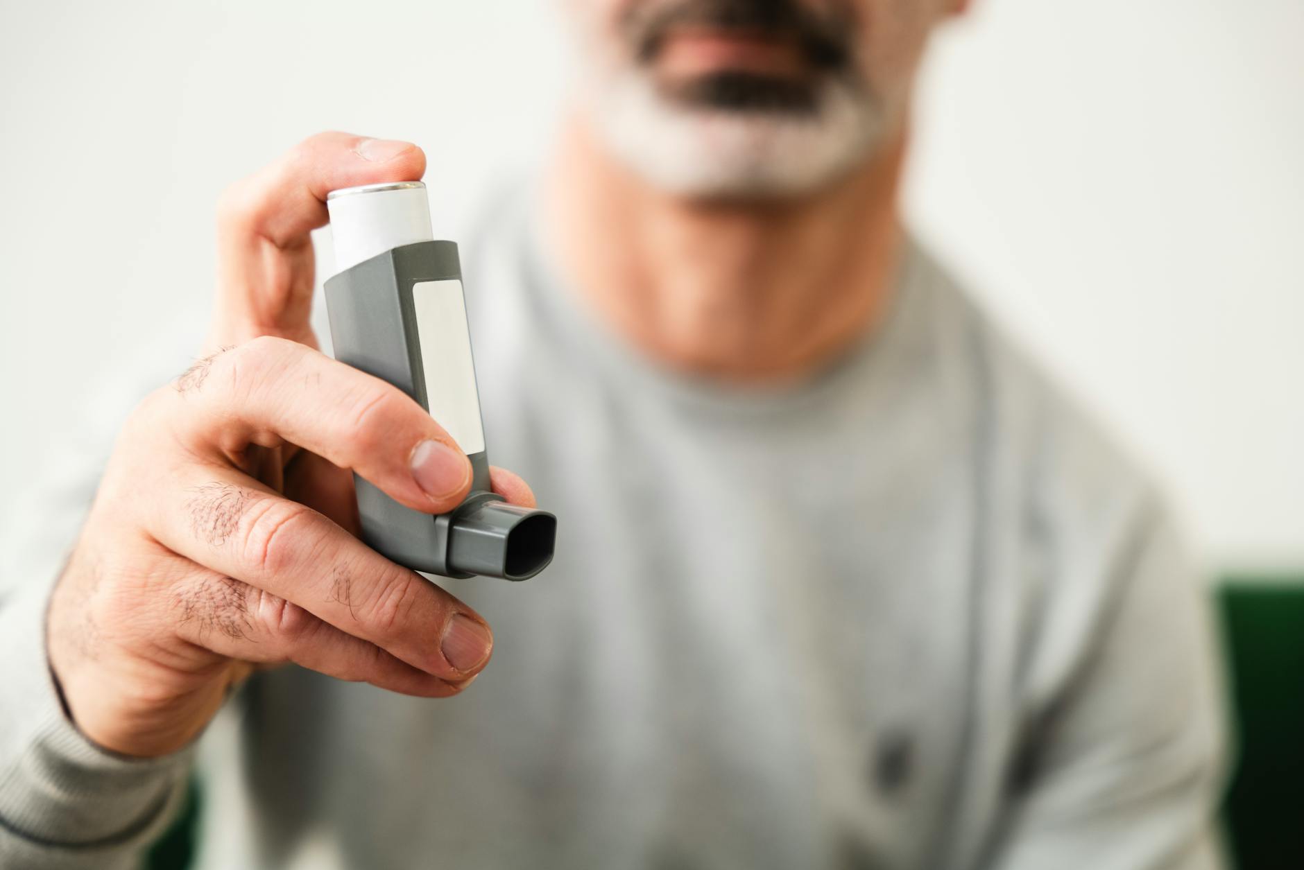 Man using an inhaler for respiratory health indoors. - allergy mental health