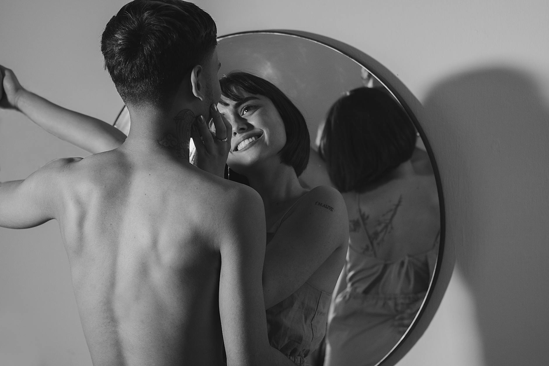 A romantic black and white photograph of a couple sharing an intimate moment, reflected in a mirror. - anxious attachment style