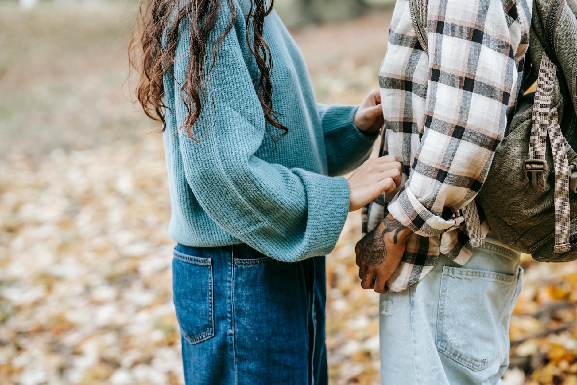 A couple sharing a tender moment in a park during fall, surrounded by leaves. - anxious attachment style