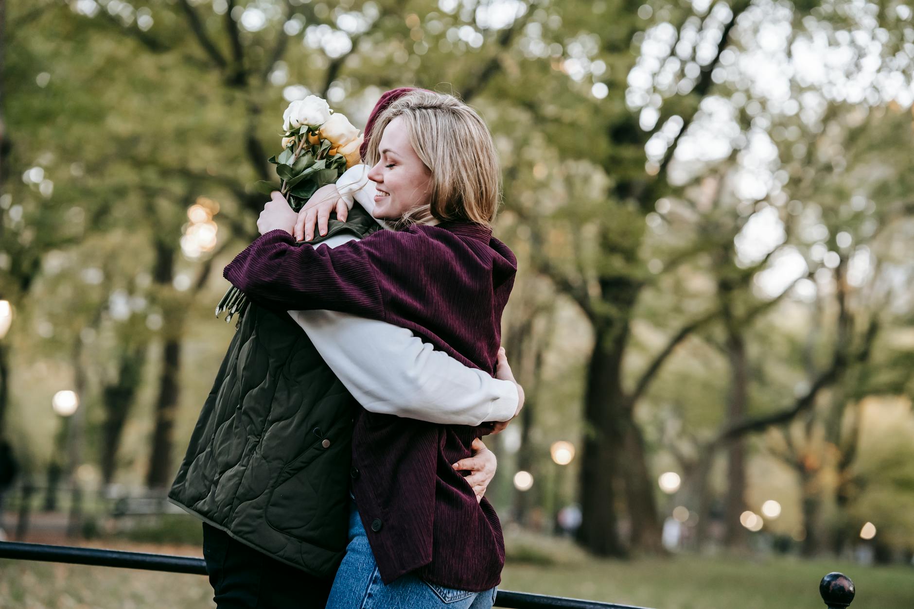 Side view of happy young couple in casual outfits with bouquet of flowers embracing in park - how to apologize to a guy