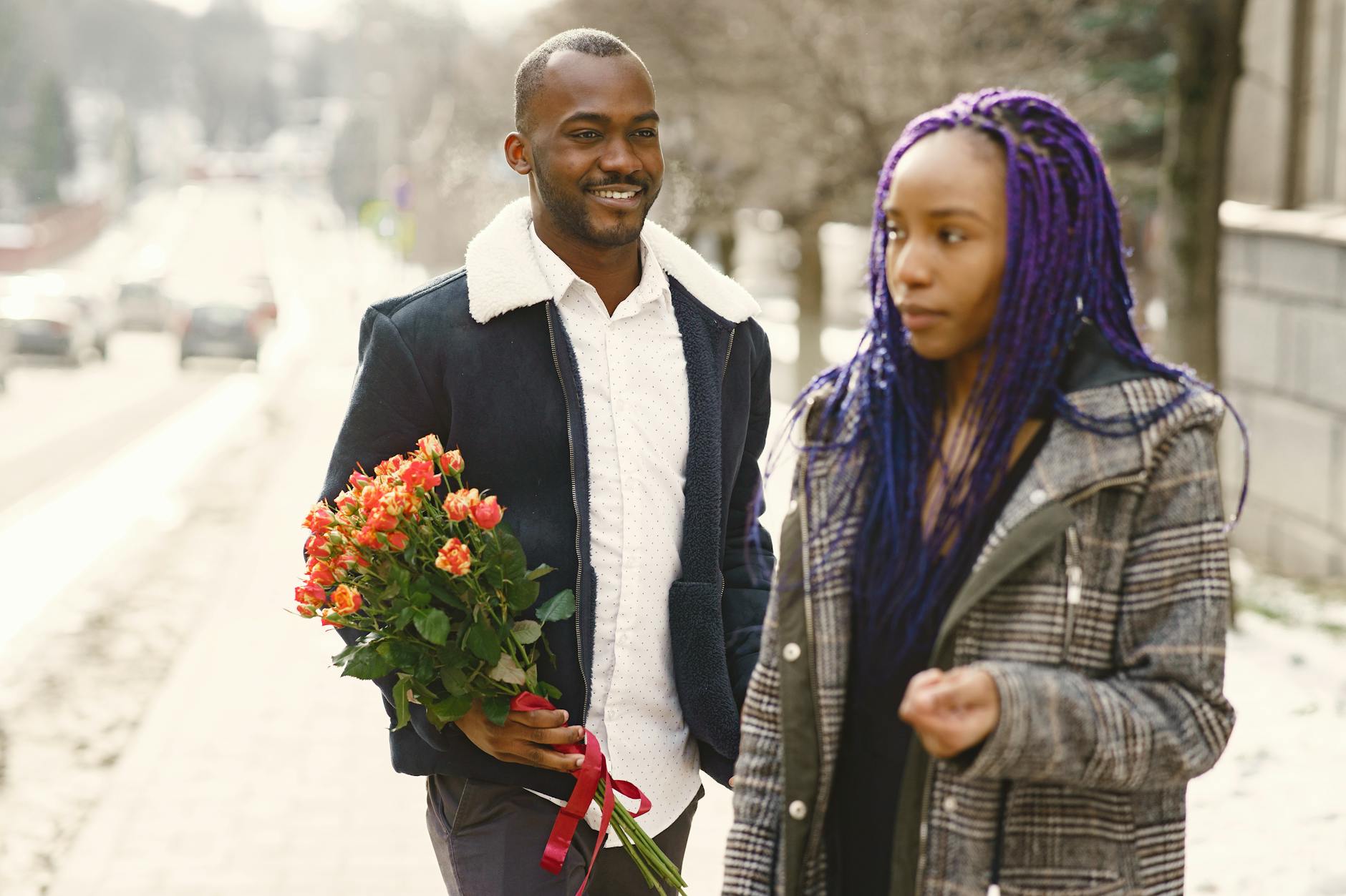 A couple strolling outdoors with a bouquet of flowers, sharing a moment of love. - how to apologize to a guy