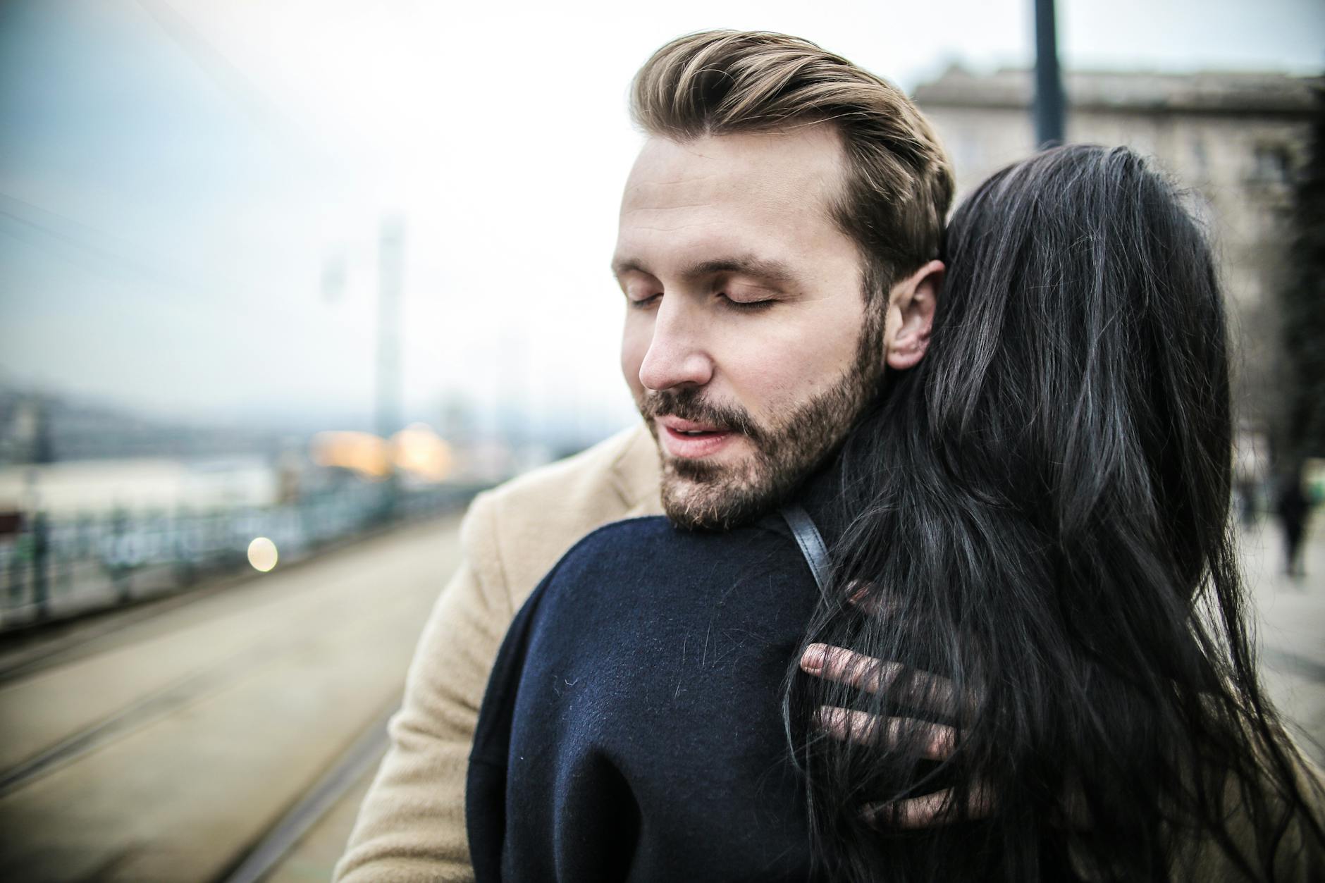 A closeup of a couple hugging warmly on a bustling city street, showcasing intimacy and affection. - how to apologize to a guy