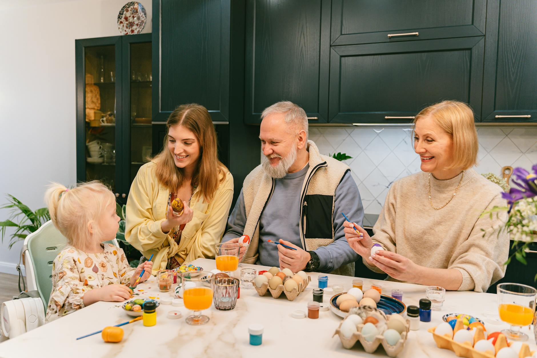 A joyful family bonding over painting Easter eggs in the kitchen, enjoying quality time. - blended family spring holidays