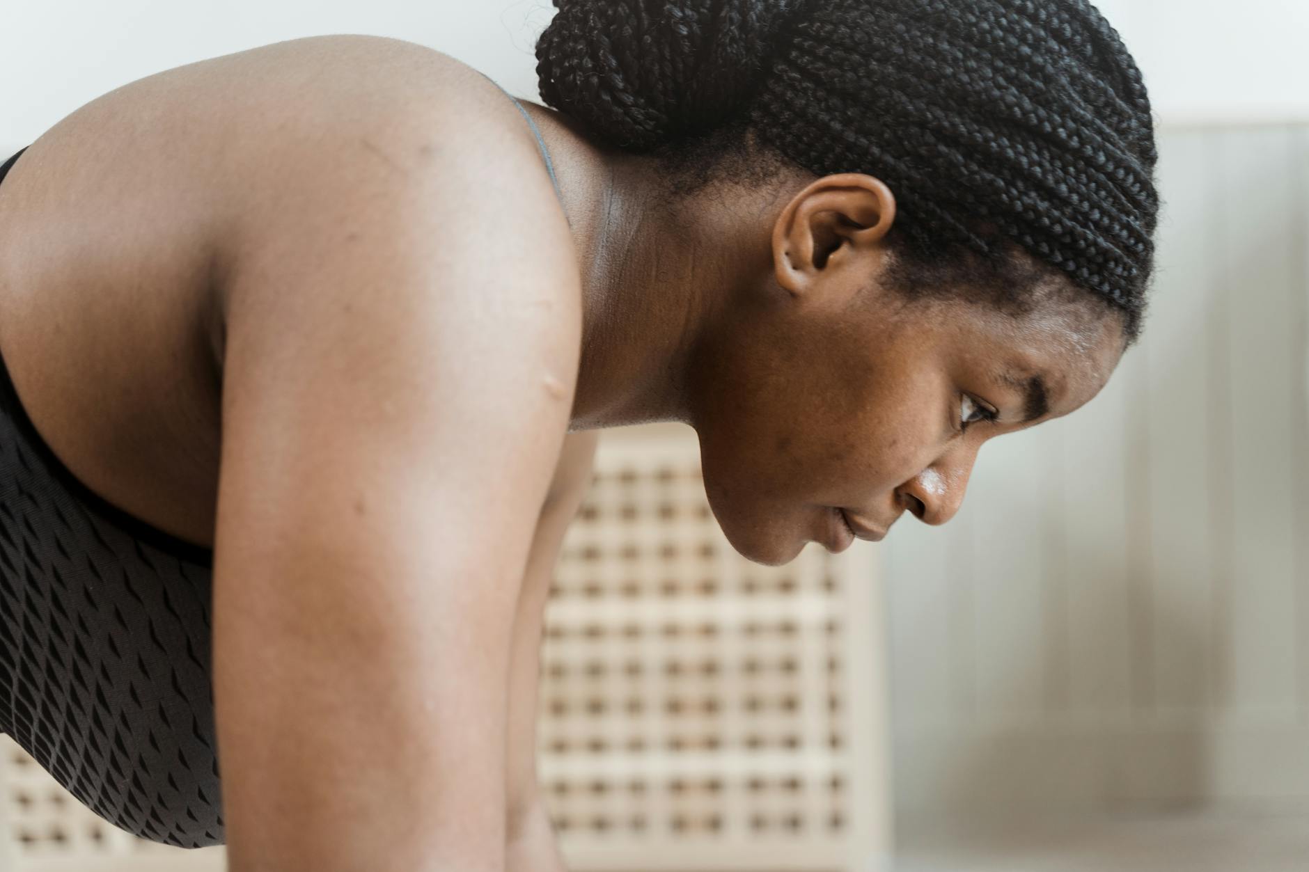 A determined woman in a black tank top doing an indoor workout, showcasing strength and fitness. - build resilience